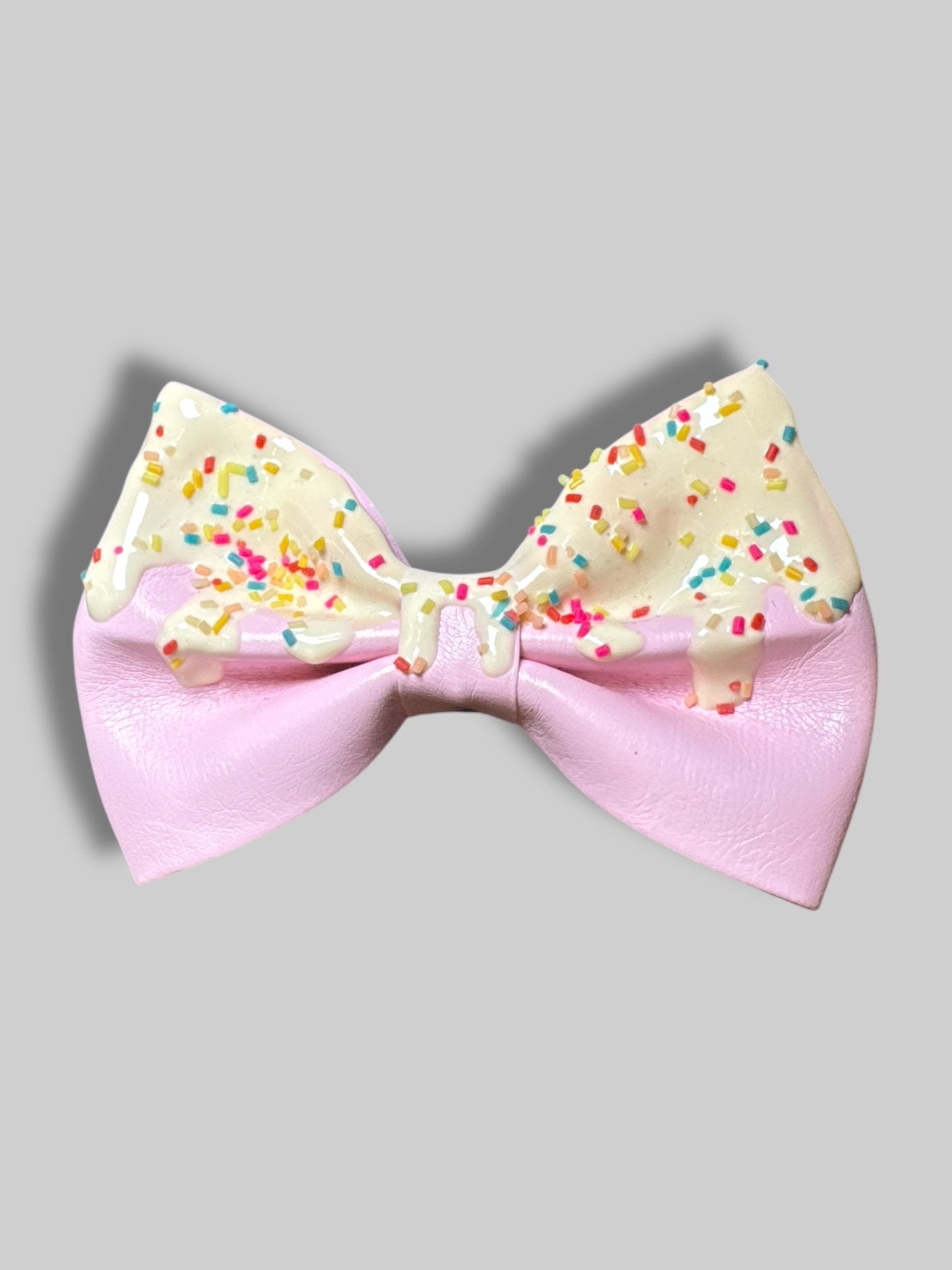 4” Pink leather bow with pin and clasp on back, and icing with sprinkle design