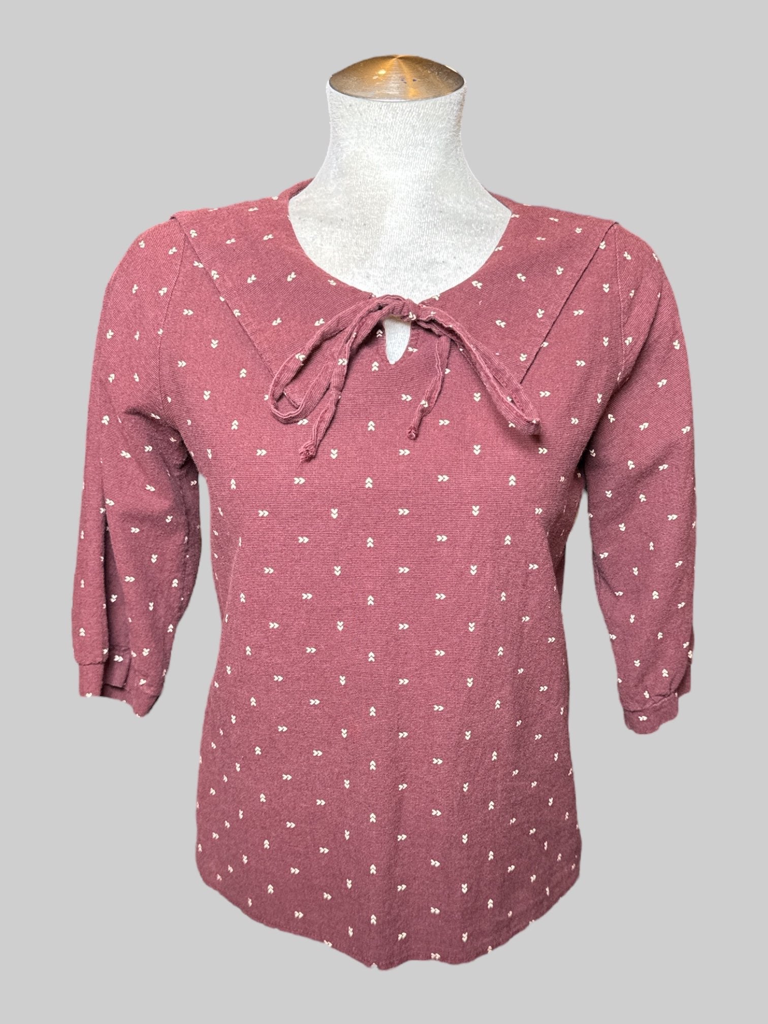 M Rich N. maroon half sleeve top with big collar, tie on front, and off white directional arrow design