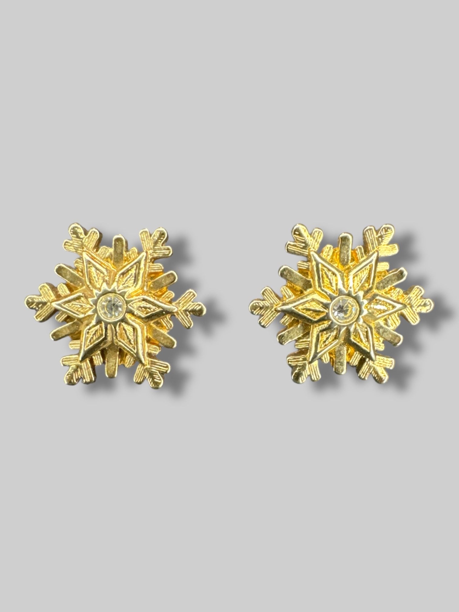 Gold snowflake shaped earrings with gem in middle