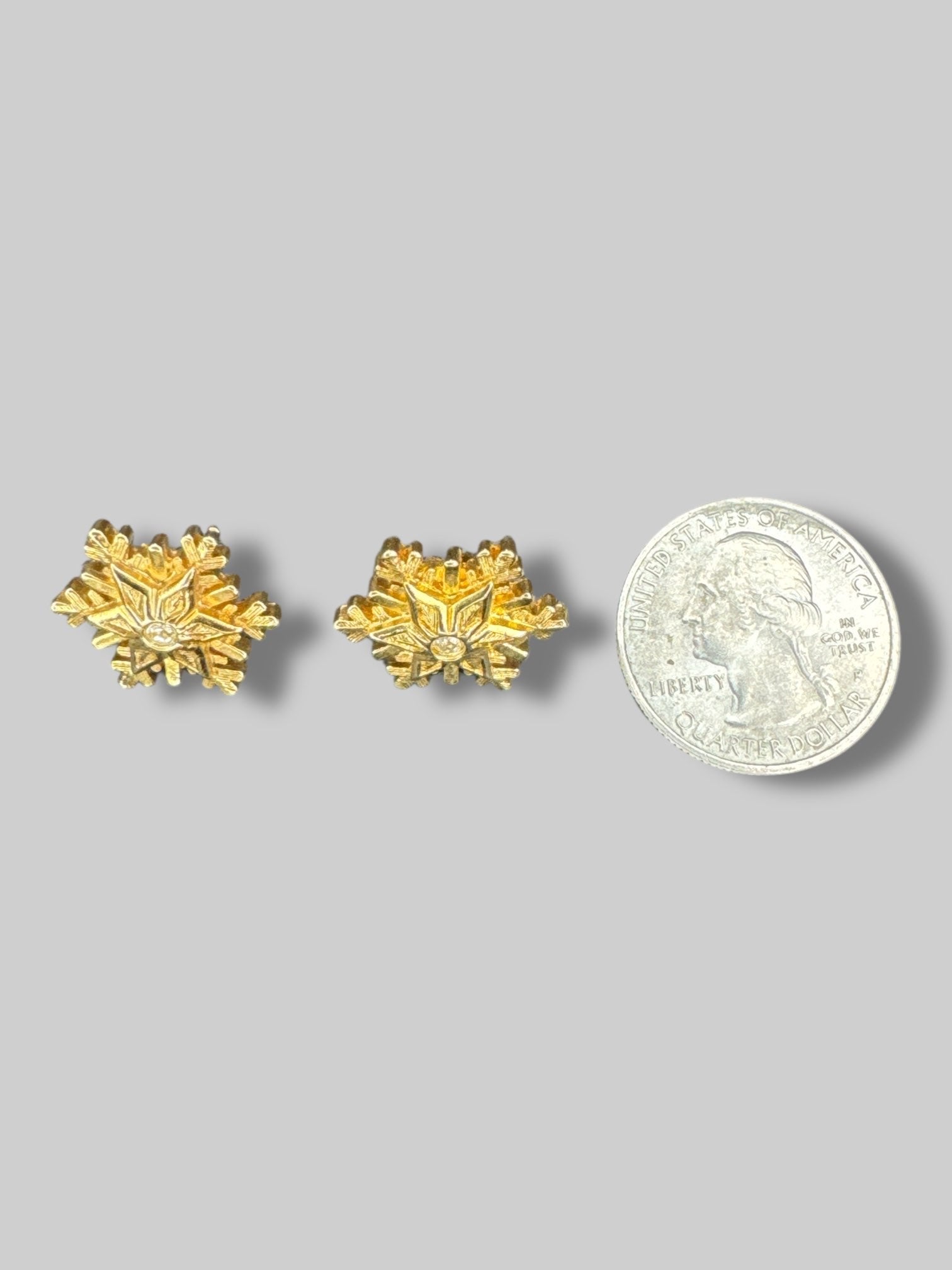 Gold snowflake shaped earrings with gem in middle