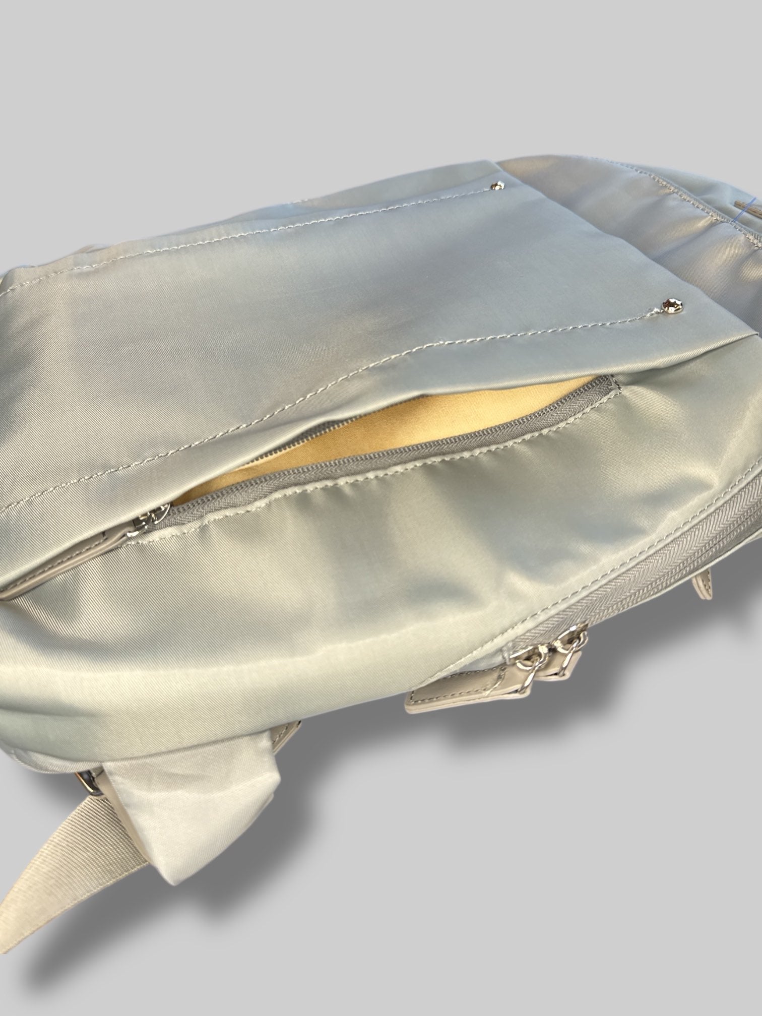 Francine Collections Silver lightly padded laptop backpack with one adjustable strap and many zipper pockets