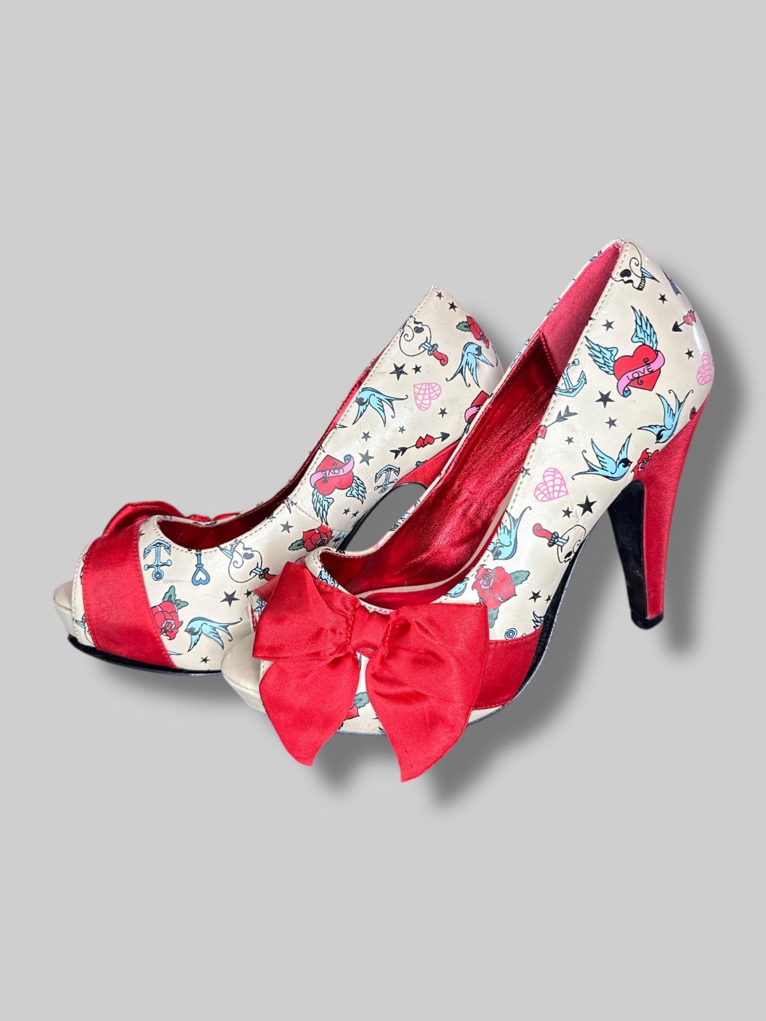 Size 6 Pin Up Couture tan stiletto heels with traditional tattoo designs, and bows on toes