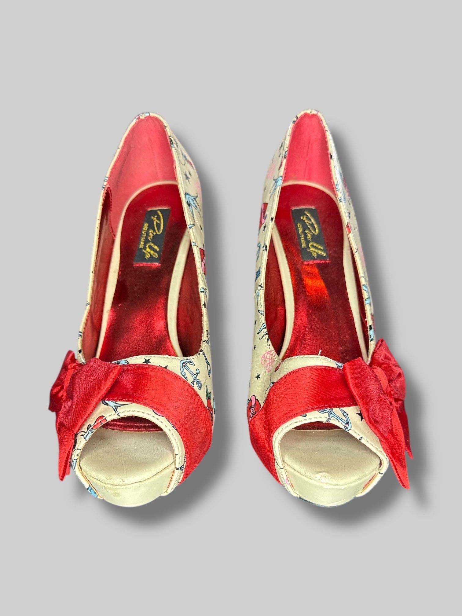 Size 6 Pin Up Couture tan stiletto heels with traditional tattoo designs, and bows on toes