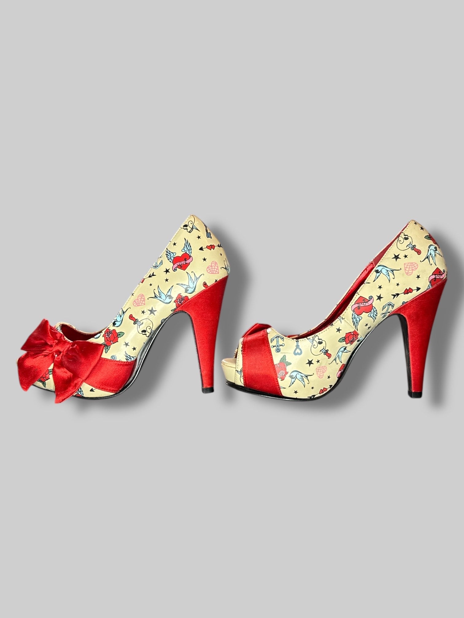 Size 6 Pin Up Couture tan stiletto heels with traditional tattoo designs, and bows on toes