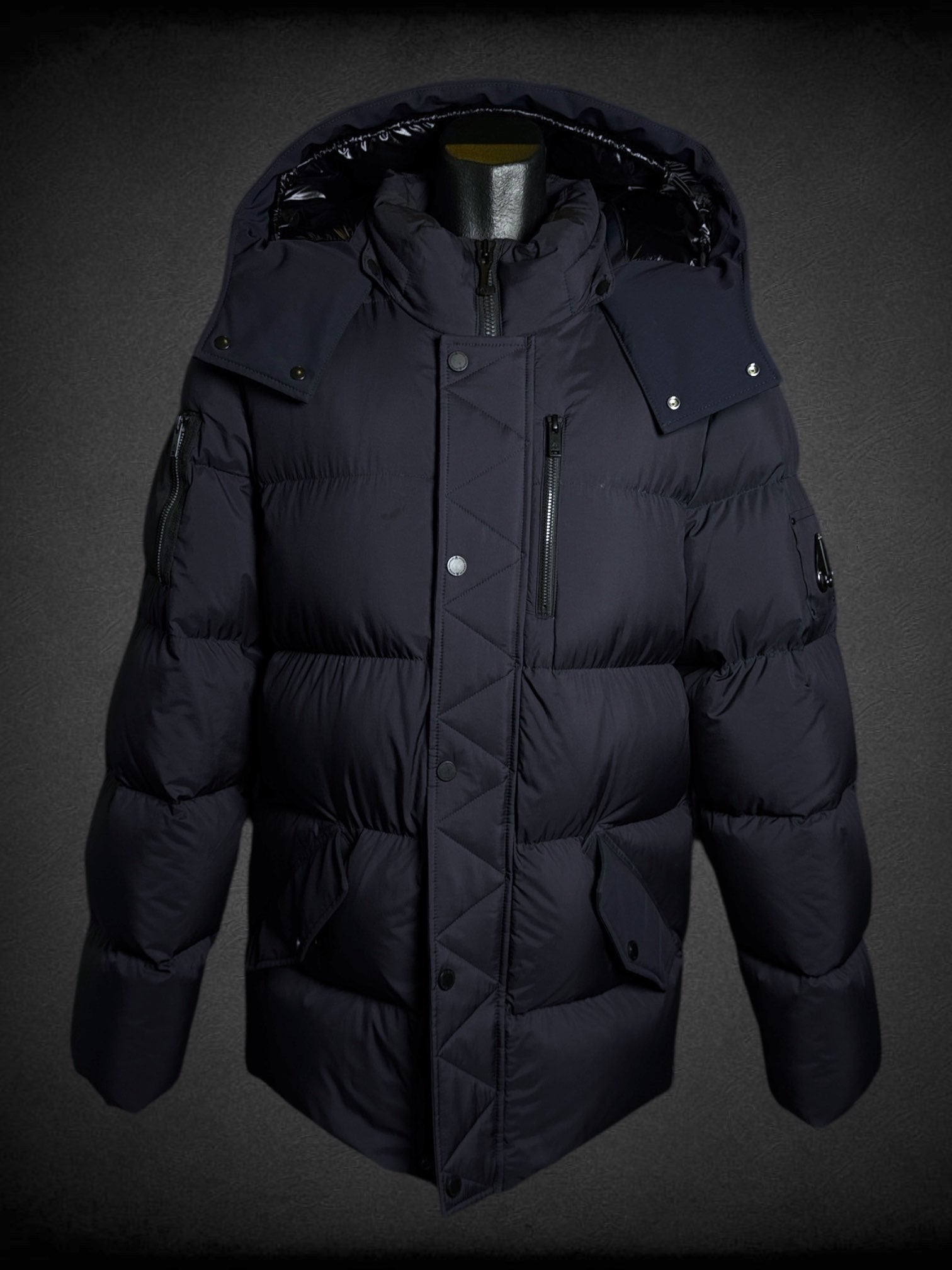 L Moose Knuckles dark blue puffer coat with zipper and snap button pockets, decorative slipper shaped like axe, and logo on sleeve