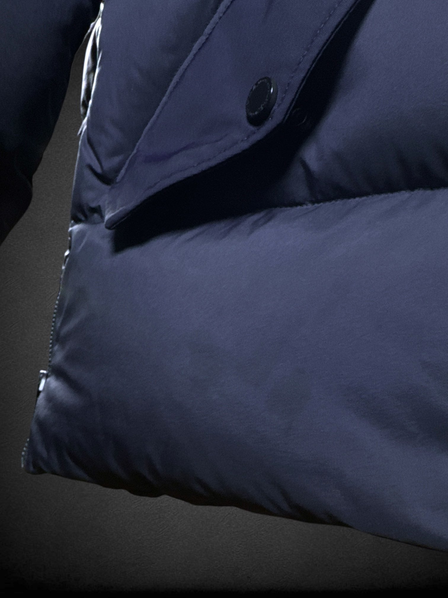 L Moose Knuckles dark blue puffer coat with zipper and snap button pockets, decorative slipper shaped like axe, and logo on sleeve