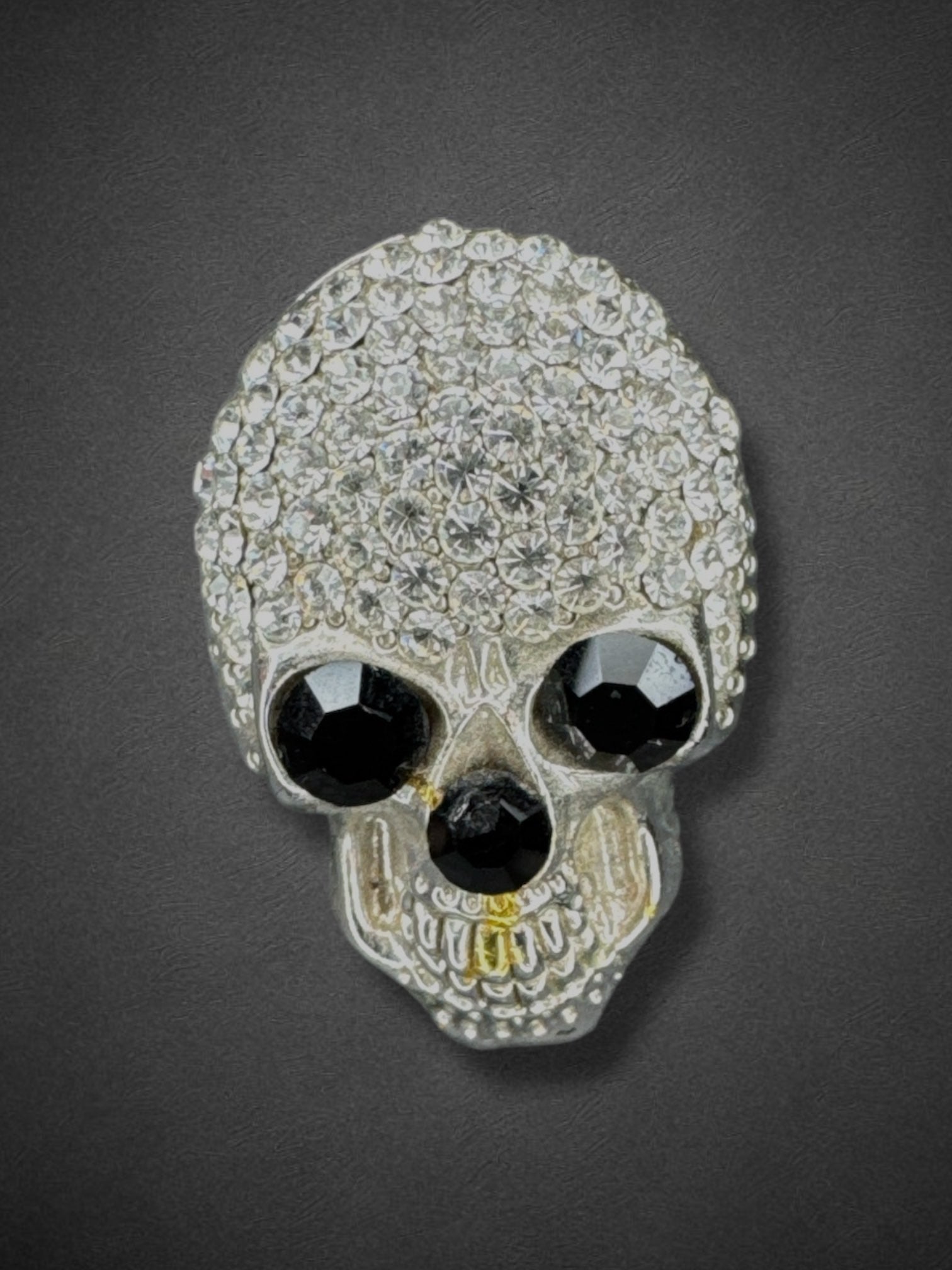 Silver tone skull brooch with black eyes and nose and some yellow