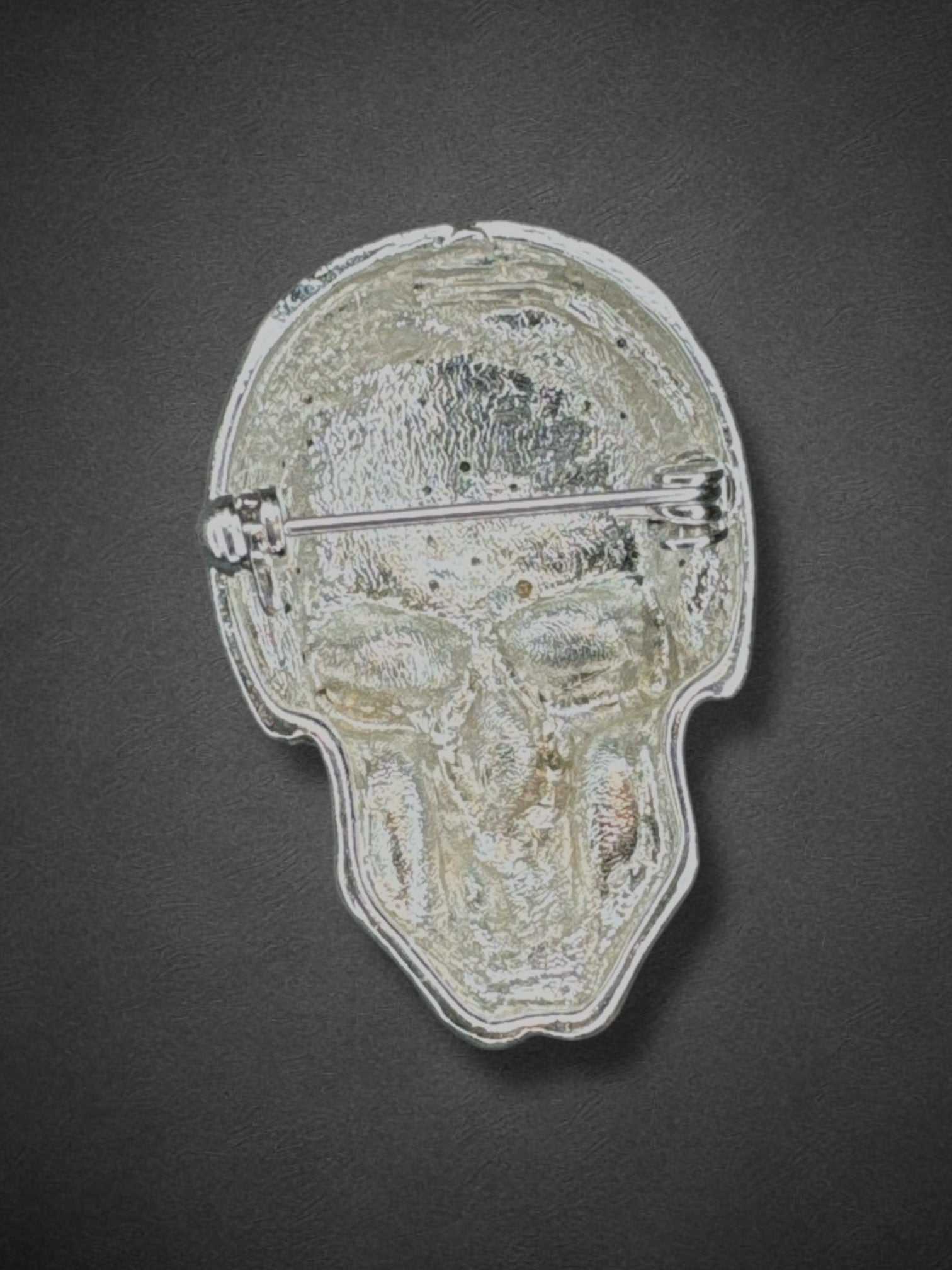 Silver tone skull brooch with black eyes and nose and some yellow