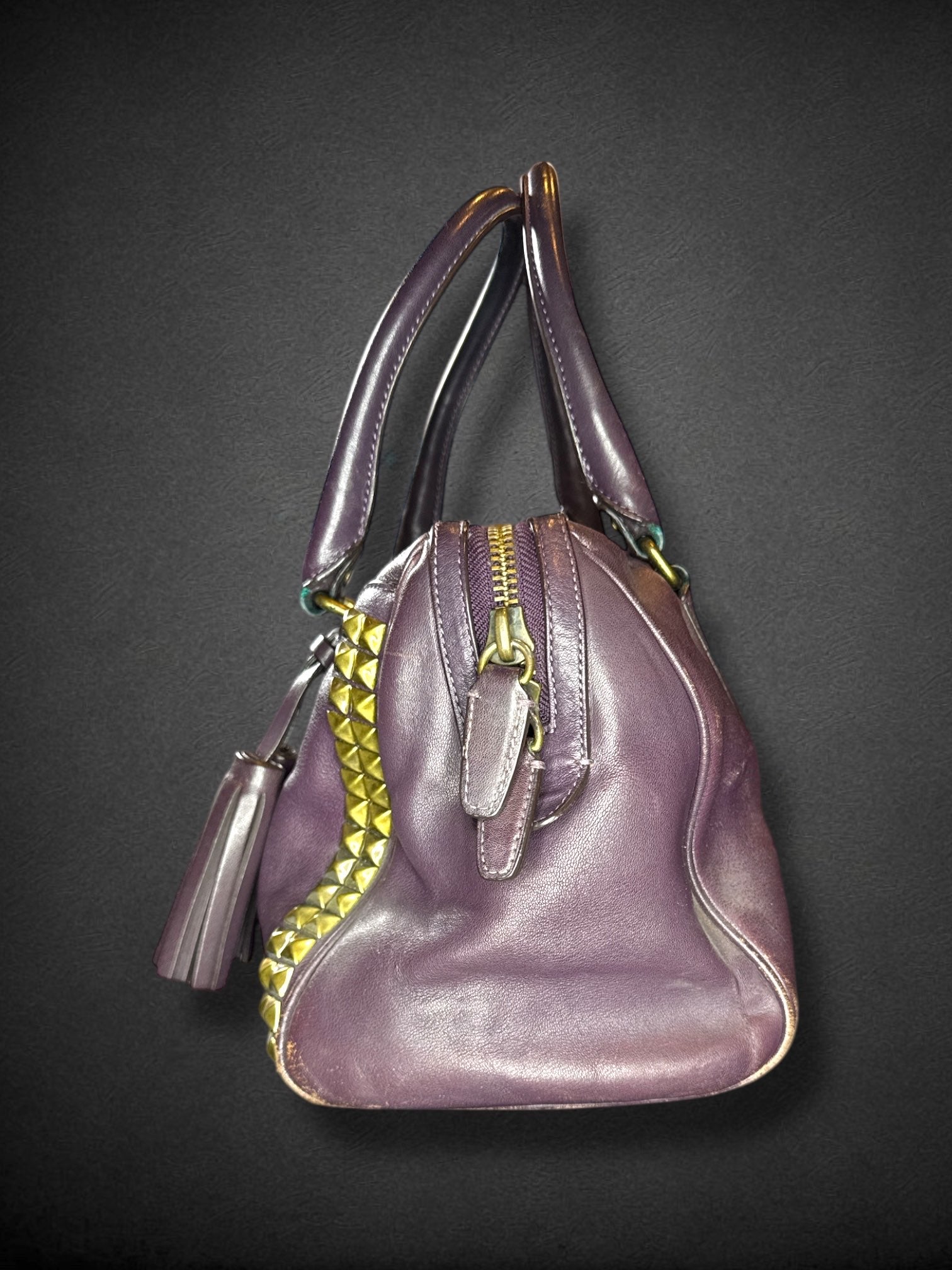 Coach purple leather purse with handles, bronze studding, and large leather tassels on front