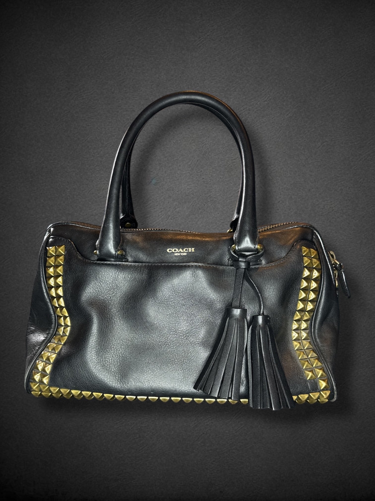 Coach black leather purse with handles, bronze studding, and large leather tassels on front