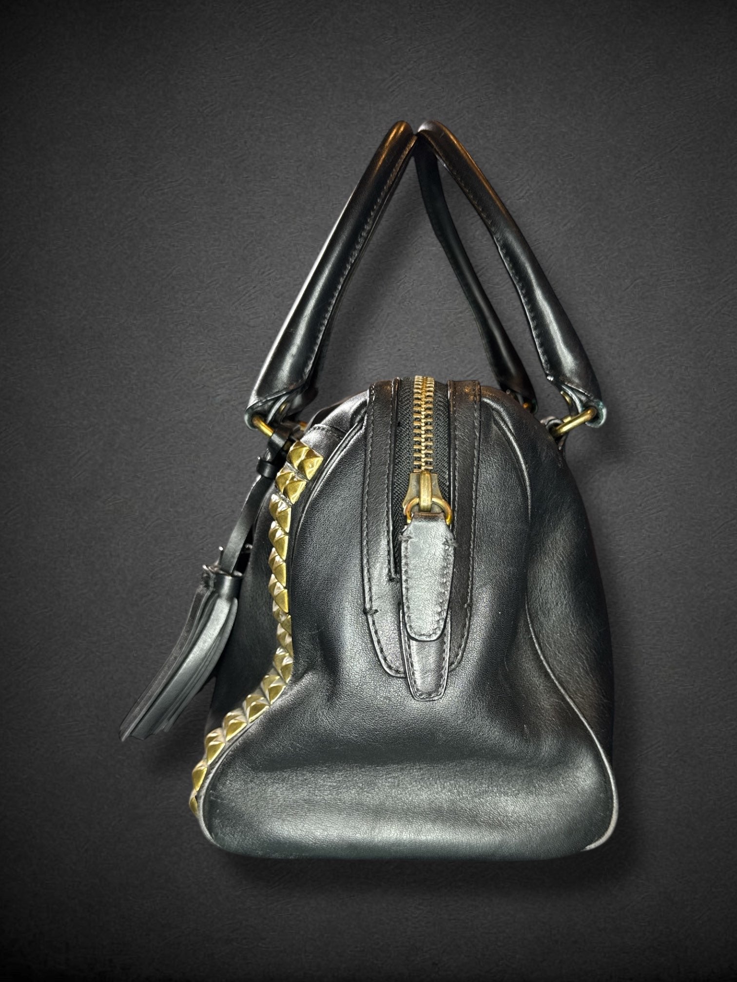 Coach black leather purse with handles, bronze studding, and large leather tassels on front