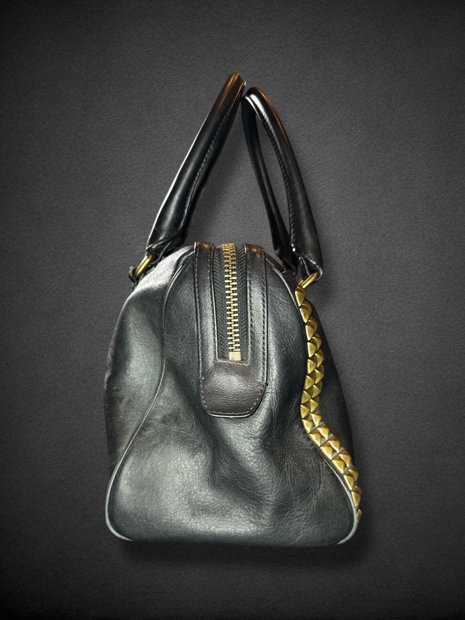 Coach black leather purse with handles, bronze studding, and large leather tassels on front