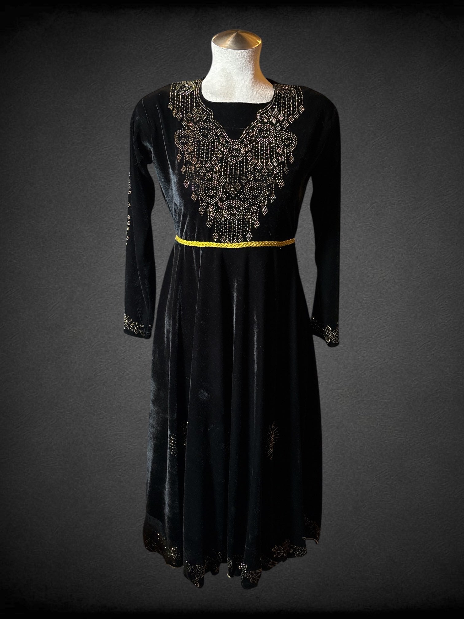 L Black velvet long sleeve dress with gold to magenta rhinestones in floral and heart designs on bodice, sleeves, skirt and hem; tie back braided gold belt and bell shaped velvet tassels