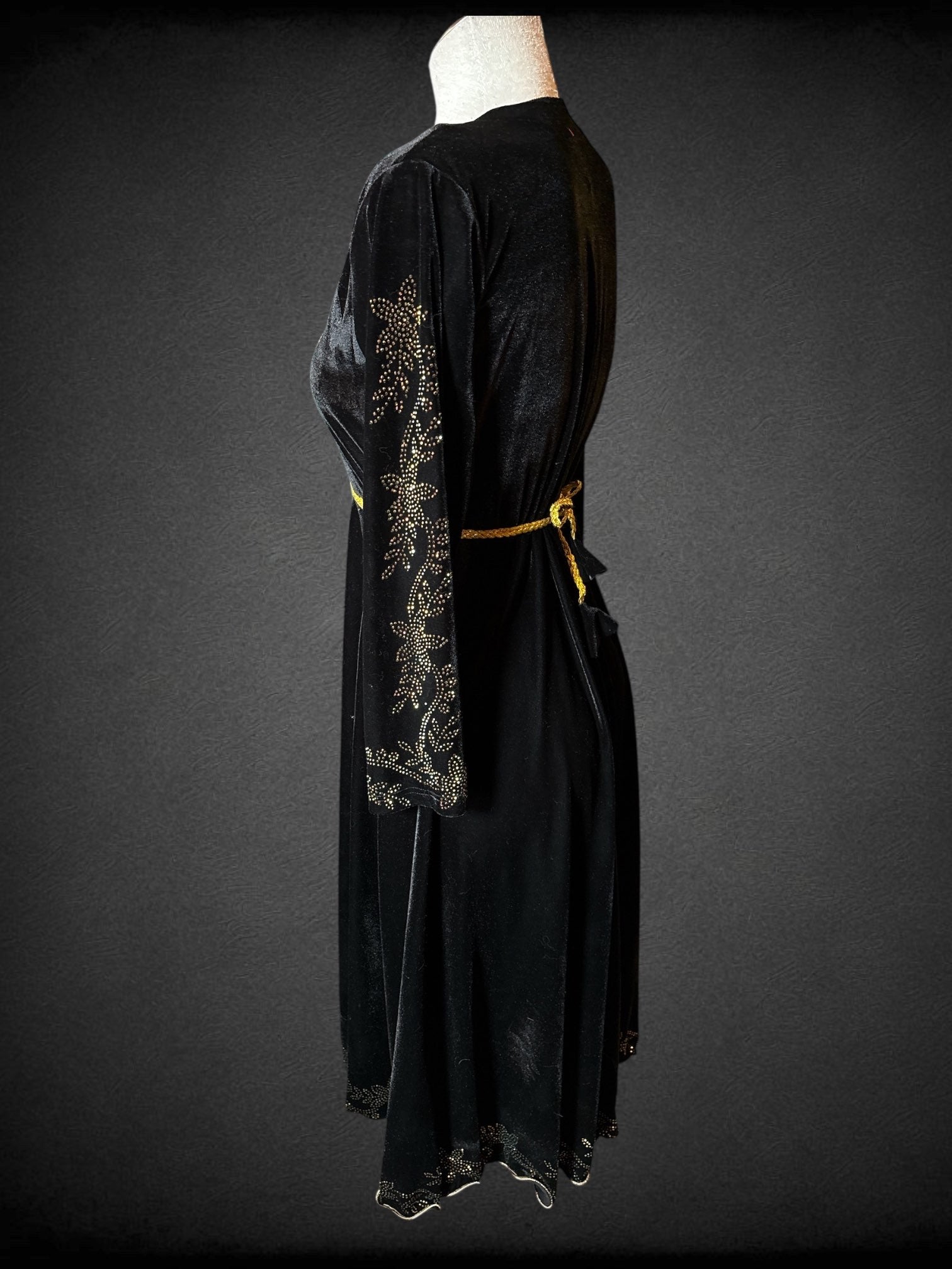 L Black velvet long sleeve dress with gold to magenta rhinestones in floral and heart designs on bodice, sleeves, skirt and hem; tie back braided gold belt and bell shaped velvet tassels