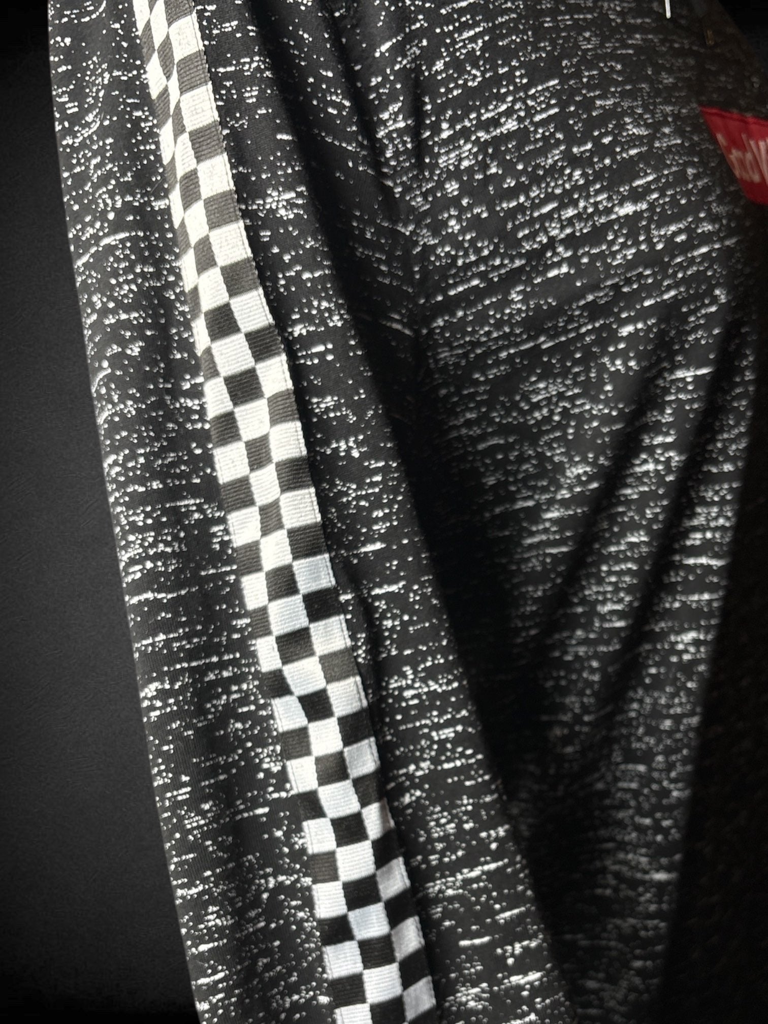 1X Brooklyn Cloth black hooded sweatshirt with white speckling, checker print appliqué on sleeves, and red “Good Vibes” appliqué on front