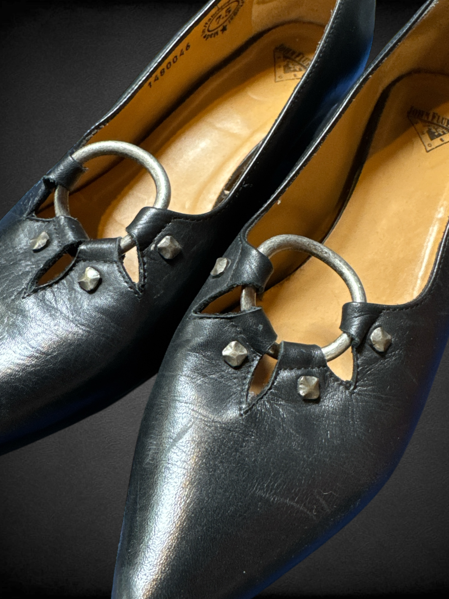 Size 7.5 John Fluevog Makena slip-on shoes featuring a pointed toe, a large metal ring, and stud detailing and dust bag included