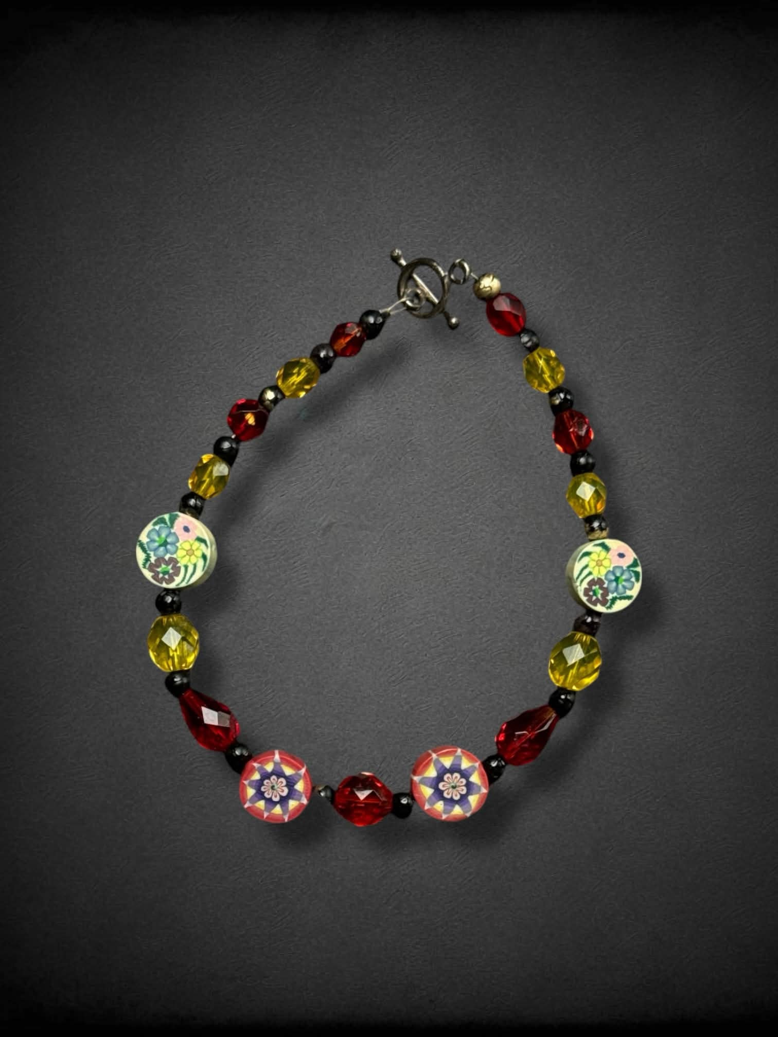 Red, black, and yellow bracelet with floral clay-cane beads