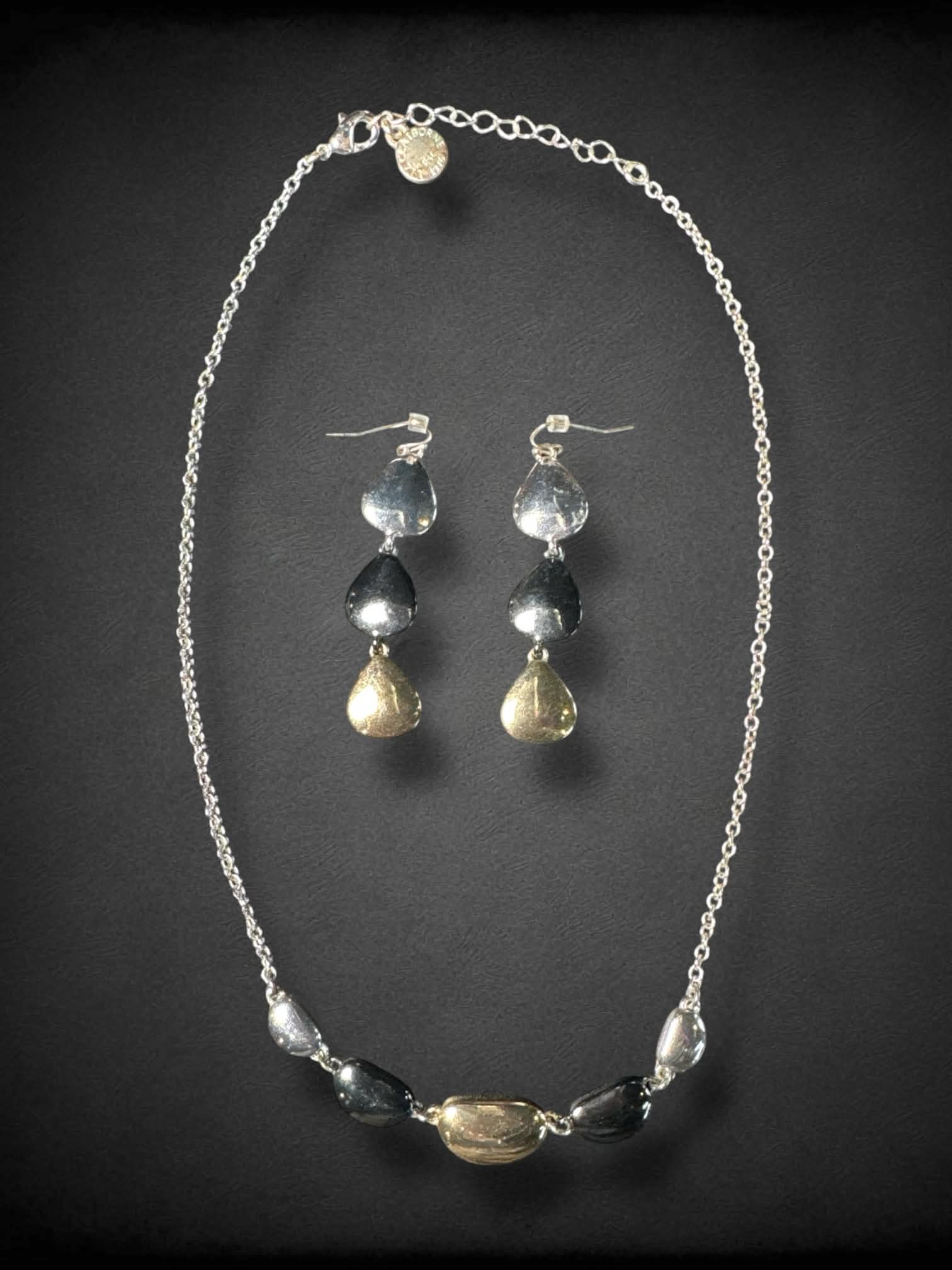 Silver toned dangle earring and necklace set with gold, silver and black toned charms.