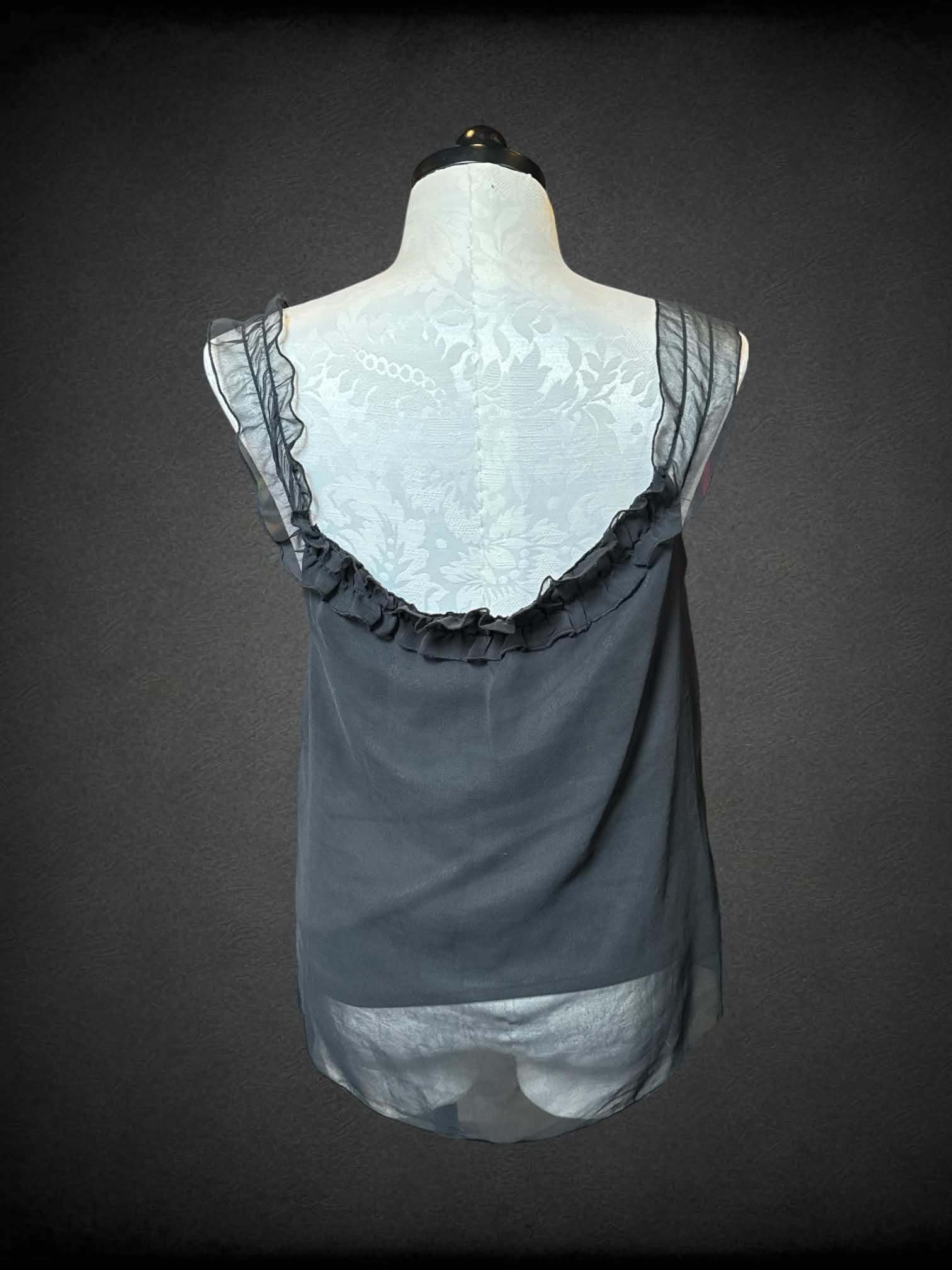 XL Pink Mode black sleeveless sheer top with lining, floral design on one strap, and ruffled neckline