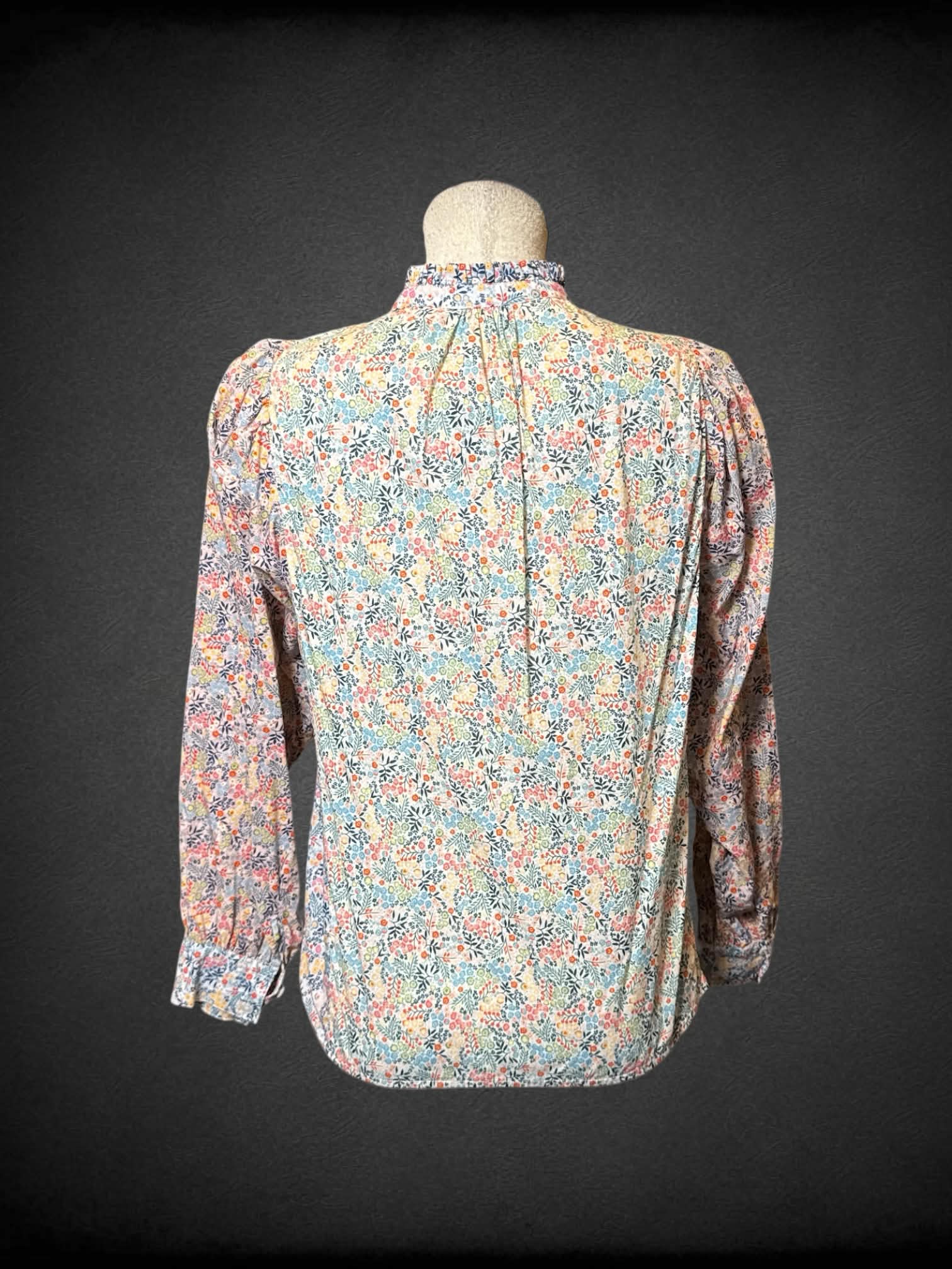 L Boden white long sleeve button up with multicolor floral design, pleating on chest, and ruffle collar