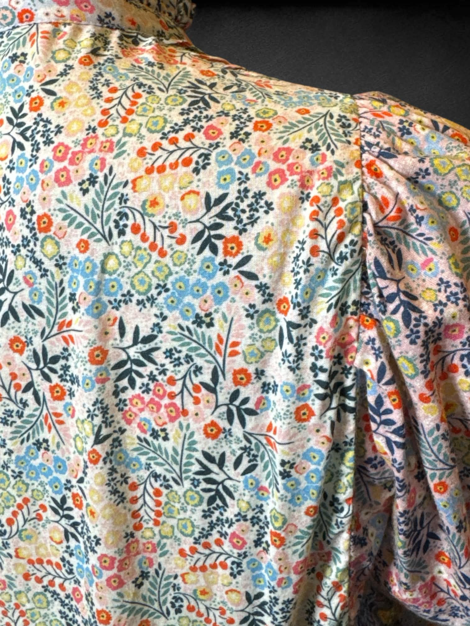 L Boden white long sleeve button up with multicolor floral design, pleating on chest, and ruffle collar