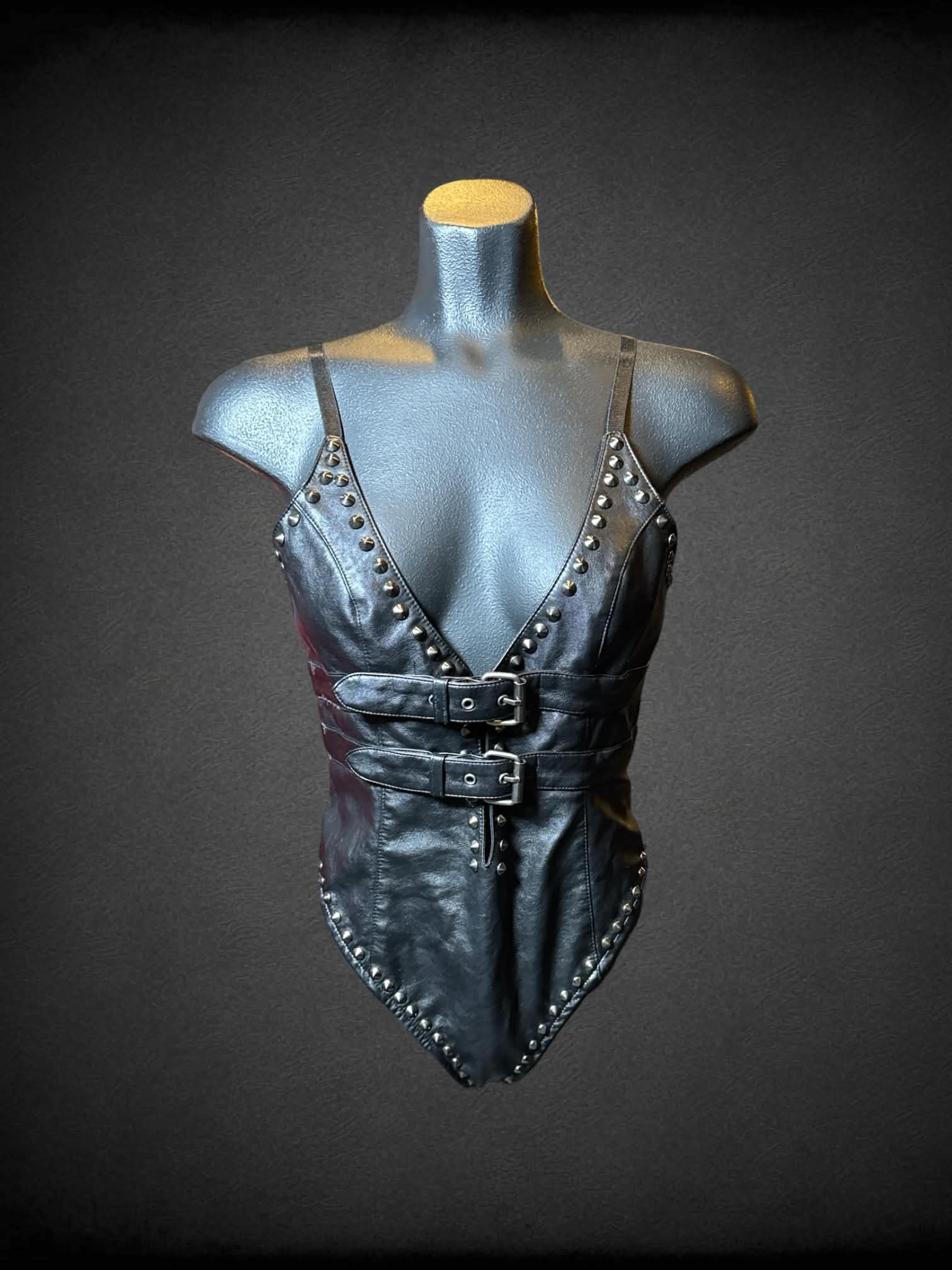 M Club Exx black leather body suit with studs, zipper on back, and buckles on front