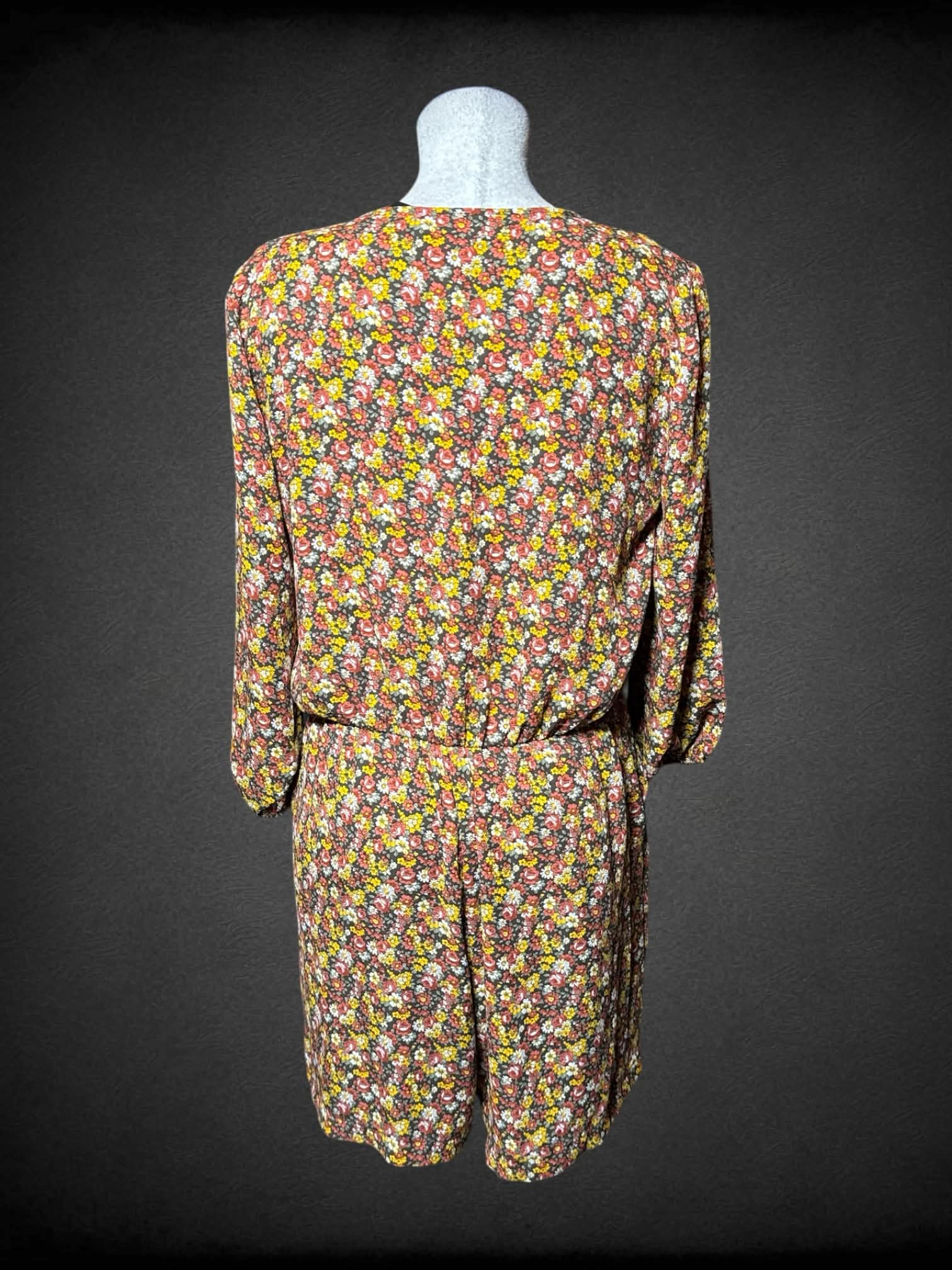 L New York Company brown jumpsuit with yellow & red floral pattern, asymmetrical neck line, and pockets