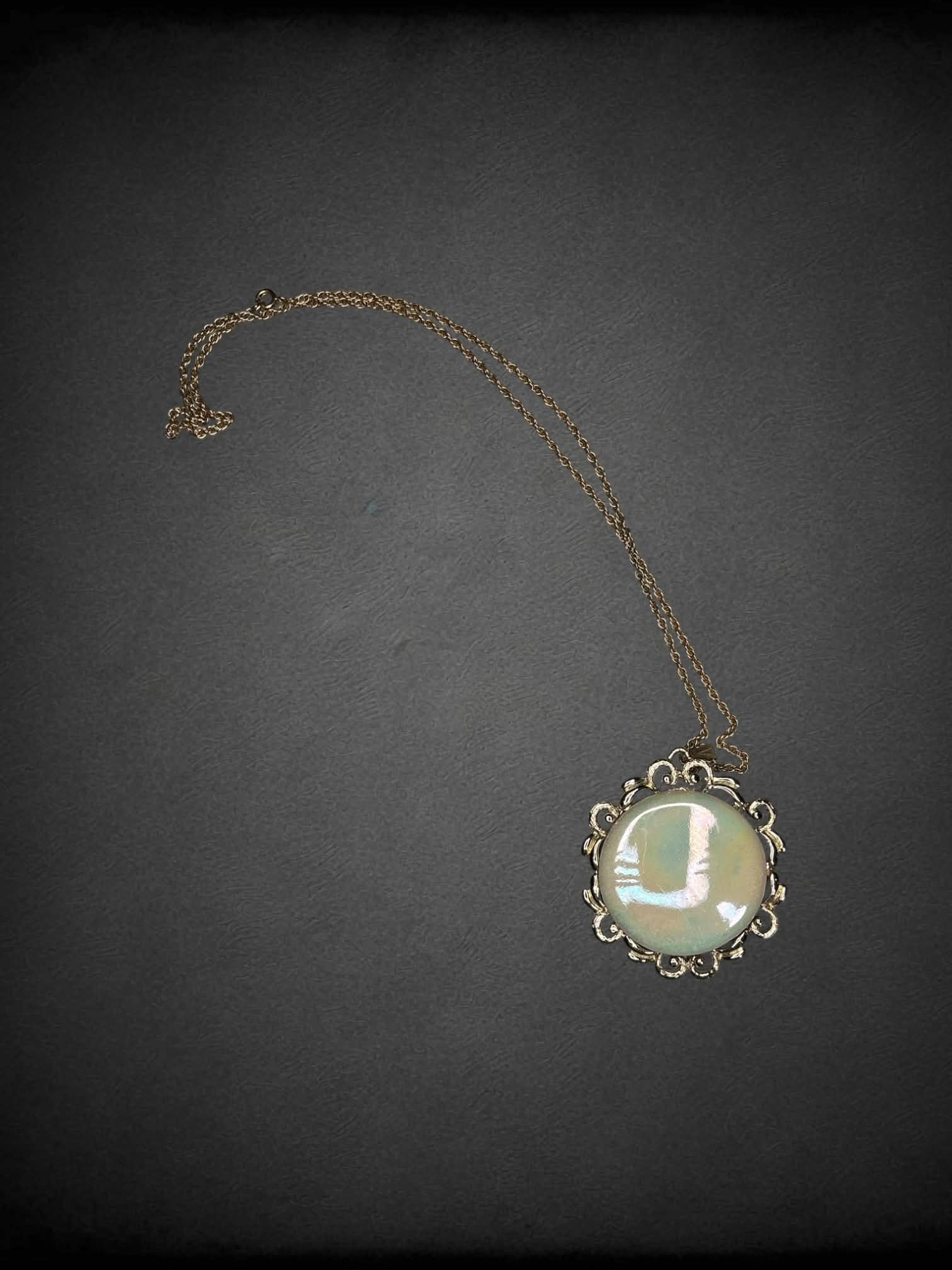 Gold chain necklace with circular opal-like broach charm