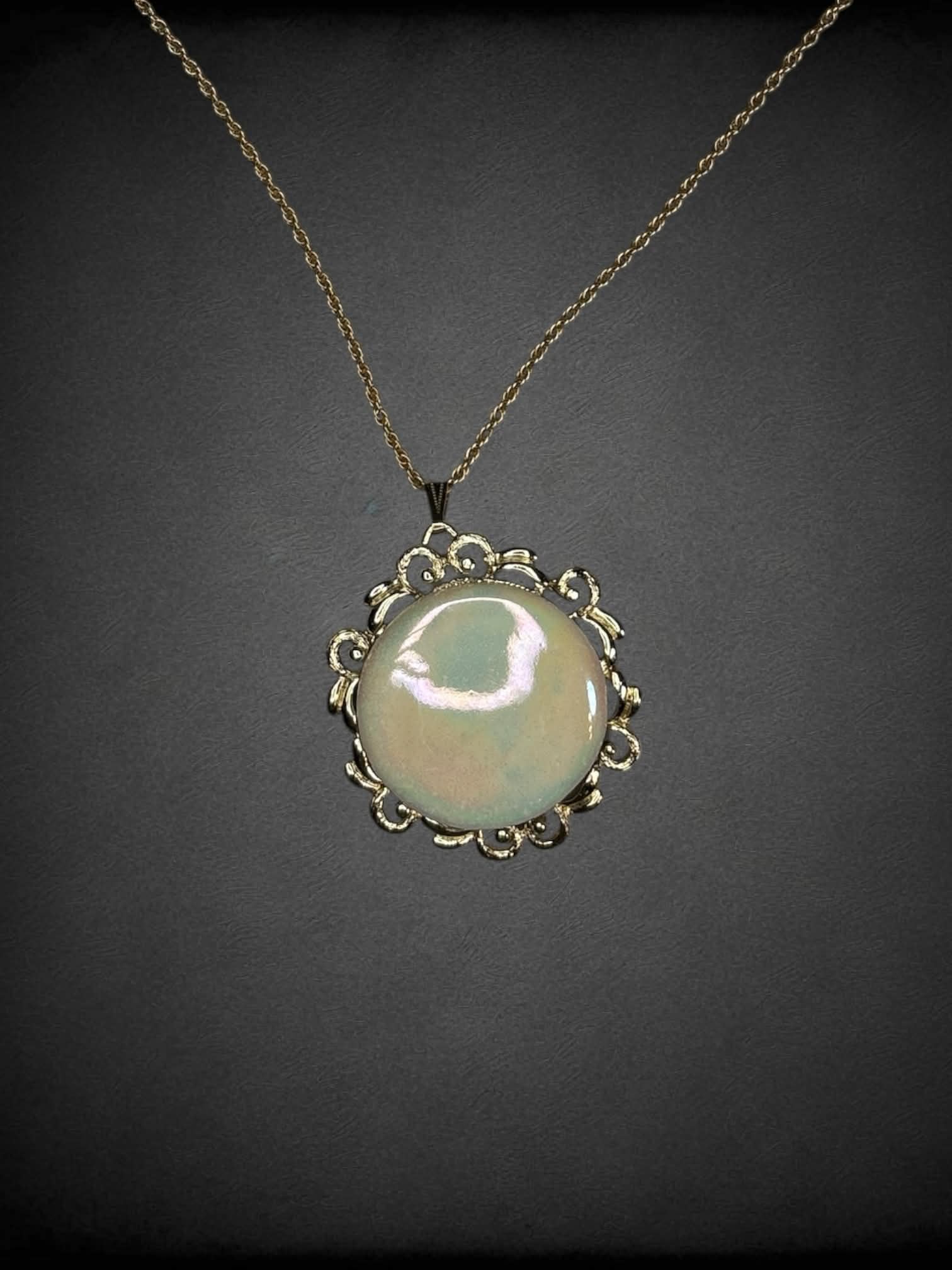 Gold chain necklace with circular opal-like broach charm
