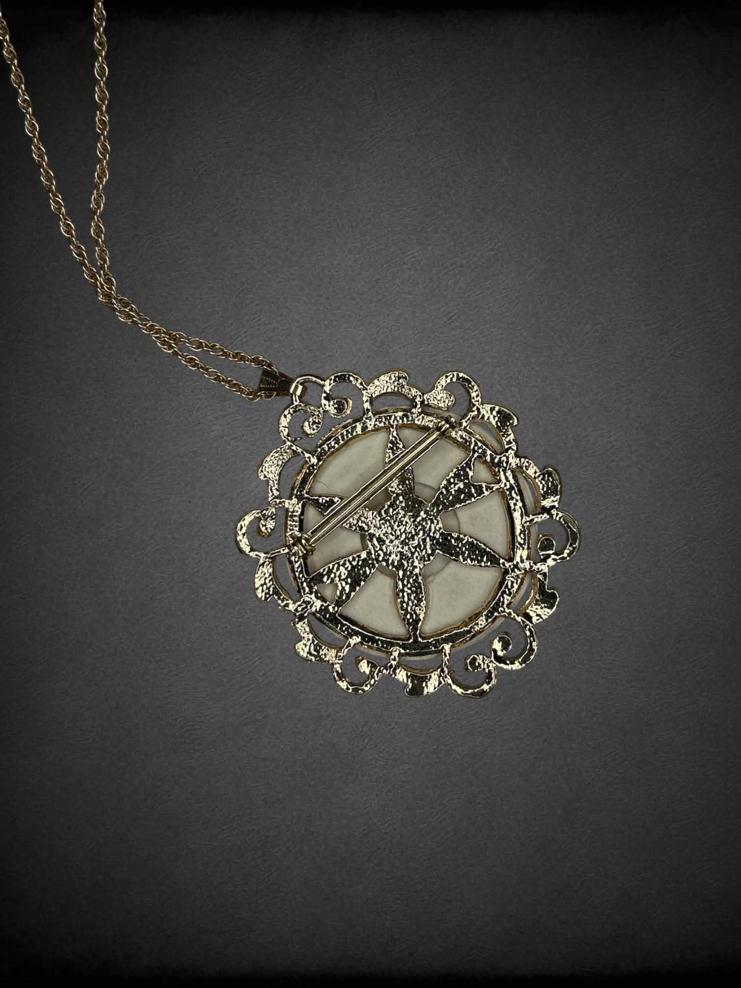 Gold chain necklace with circular opal-like broach charm