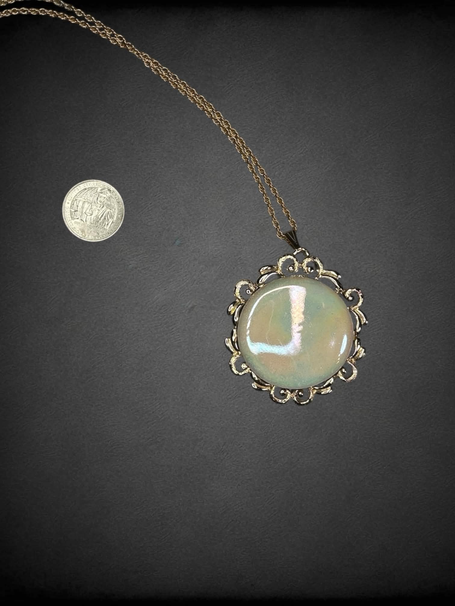 Gold chain necklace with circular opal-like broach charm