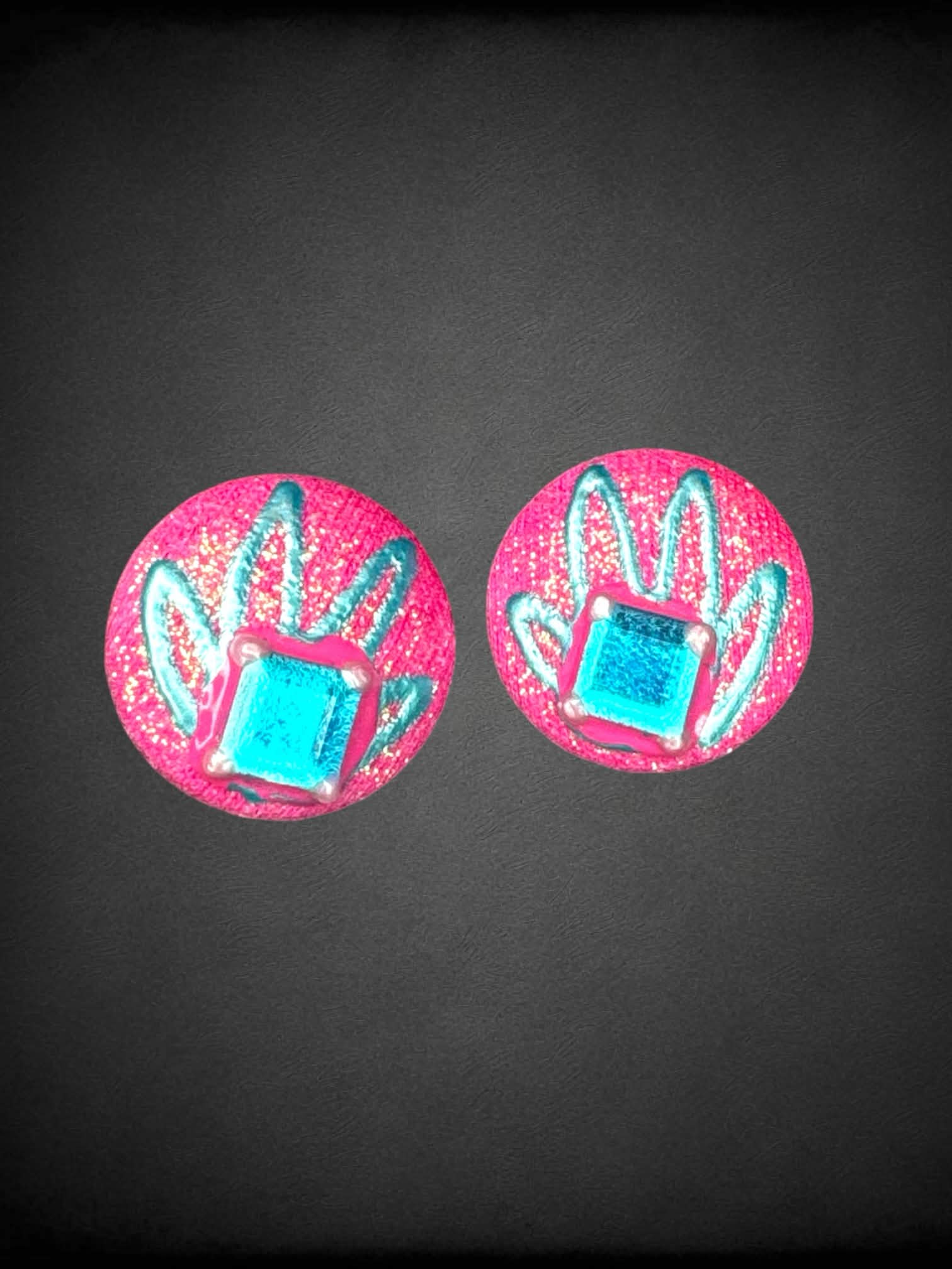 Sparkly pink circular earrings with blue gem