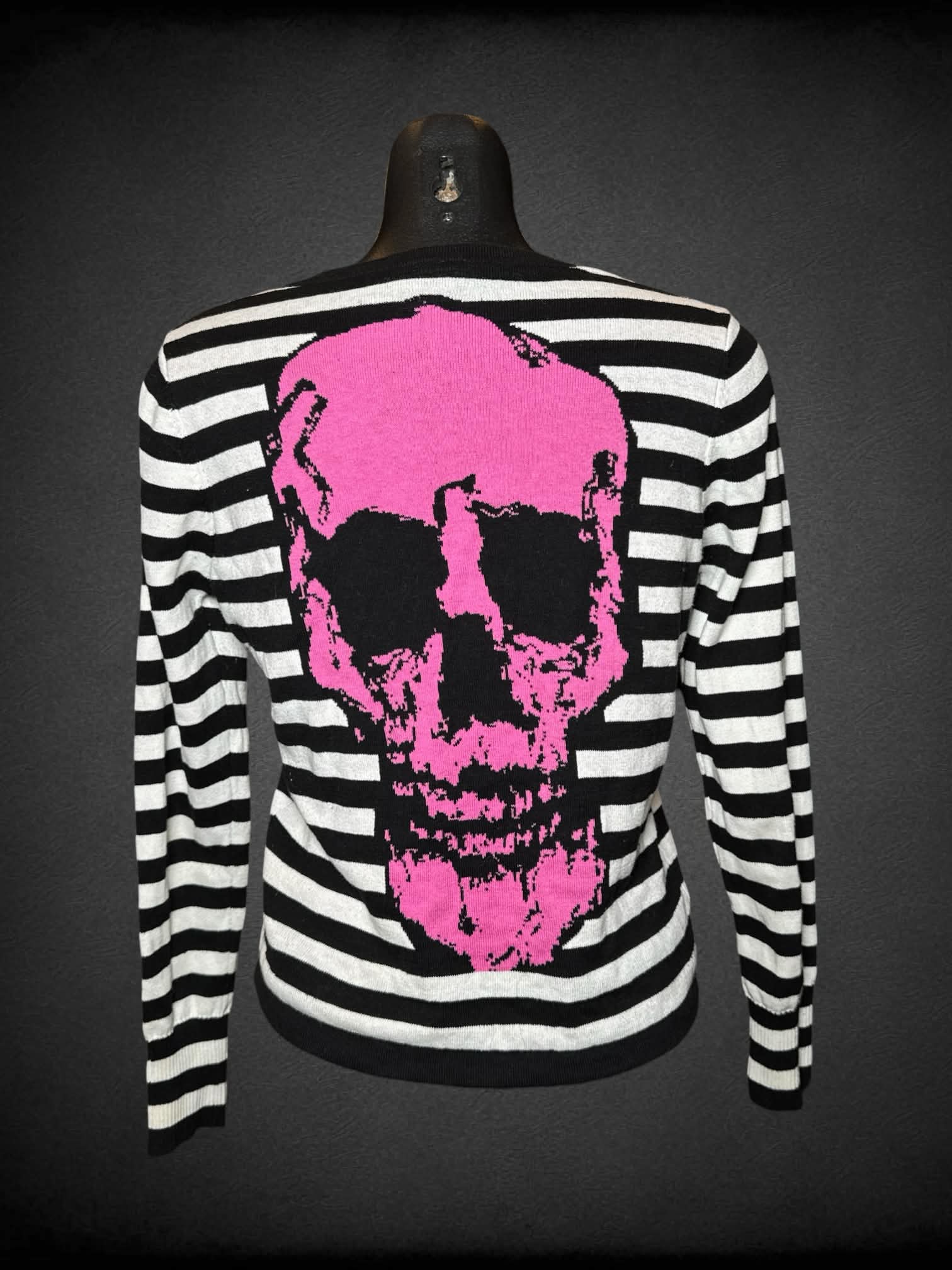 M Too Fast black & white button-up sweater with pink embroidered cross bones on front, and pink skull graphic on back