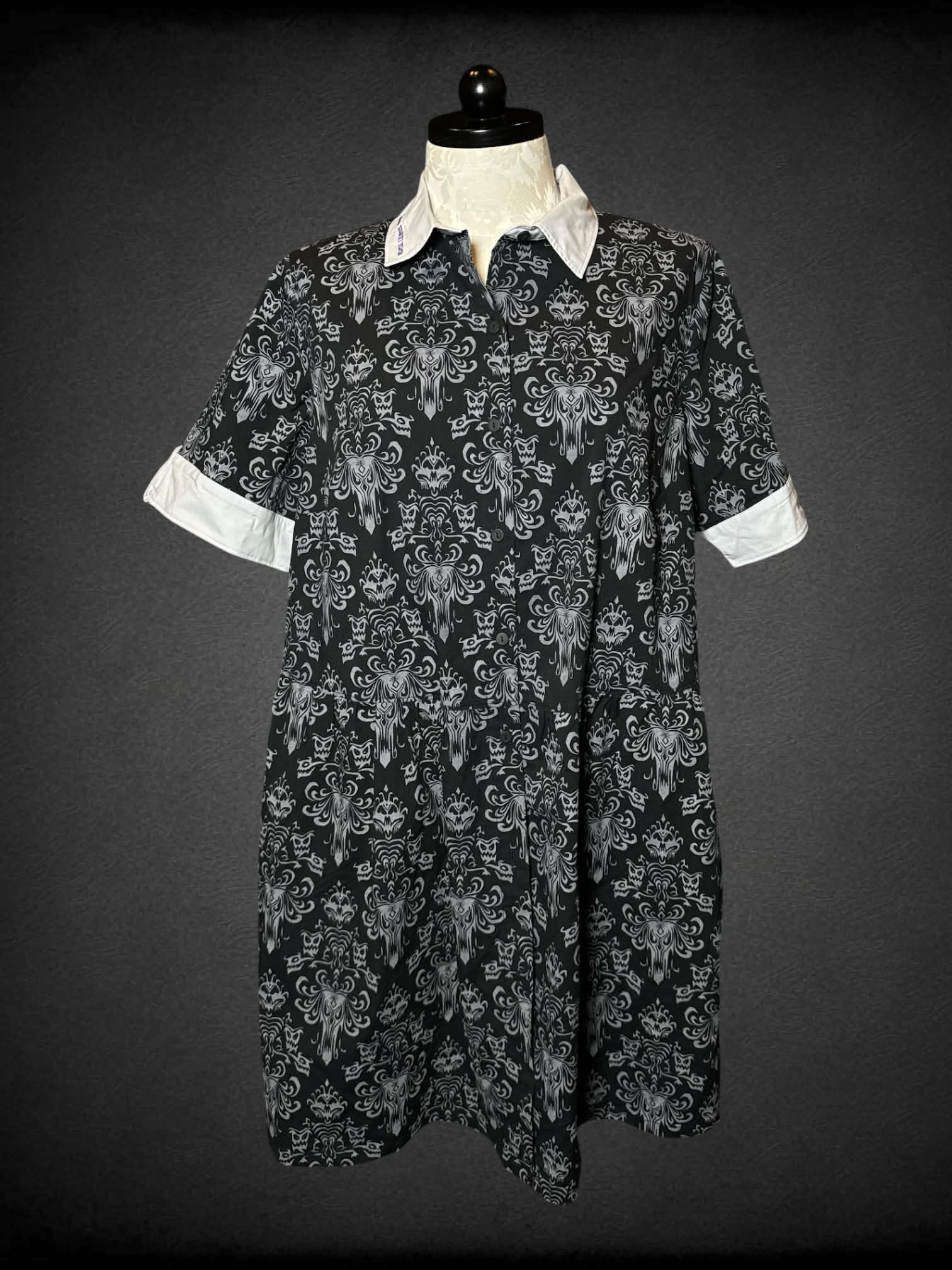 1X Disney black button-up dress with pockets, grey “Haunted Mansion” pattern, and embroidered “Tomb Sweet Tomb” writing on collar