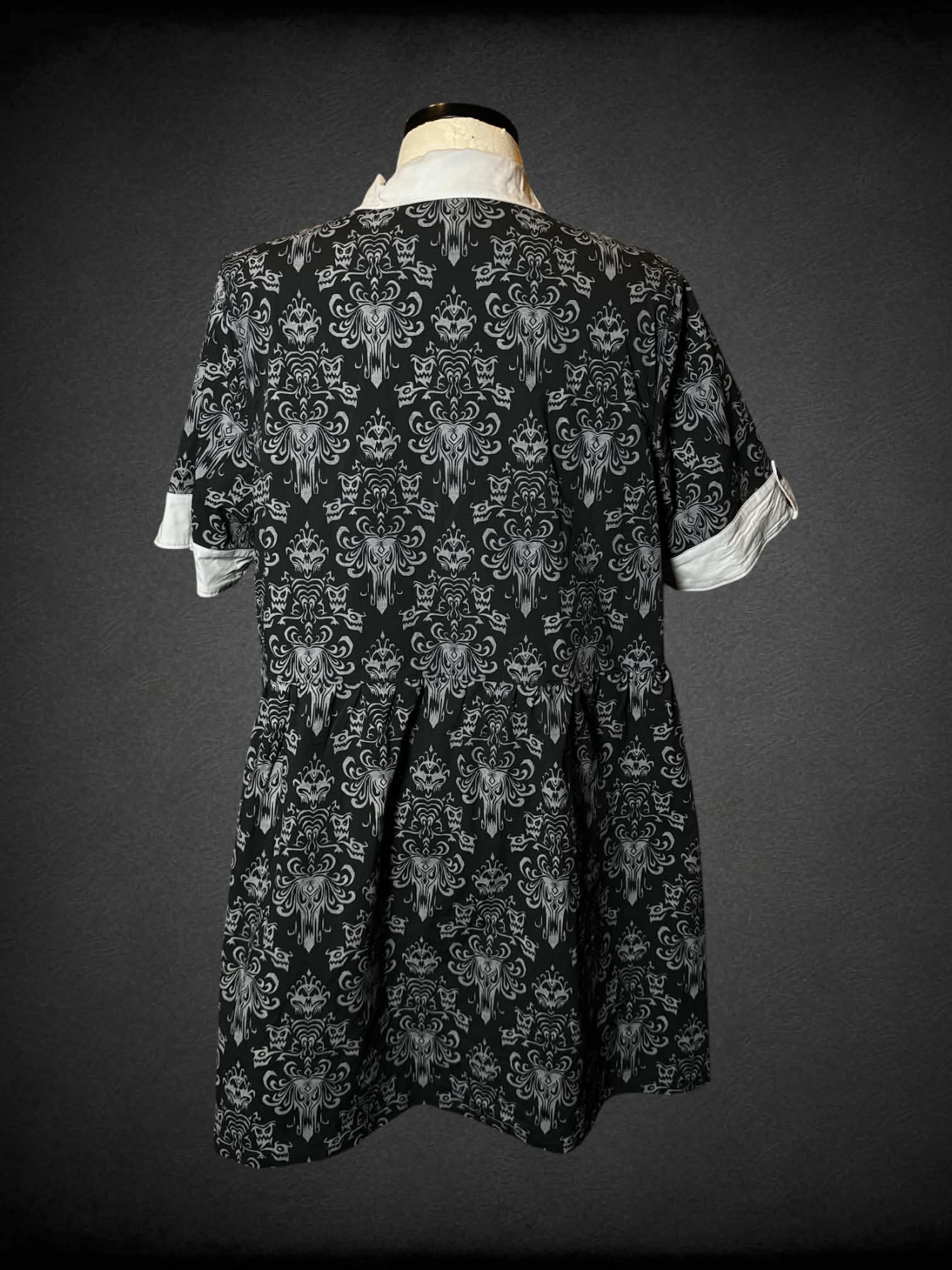 1X Disney black button-up dress with pockets, grey “Haunted Mansion” pattern, and embroidered “Tomb Sweet Tomb” writing on collar