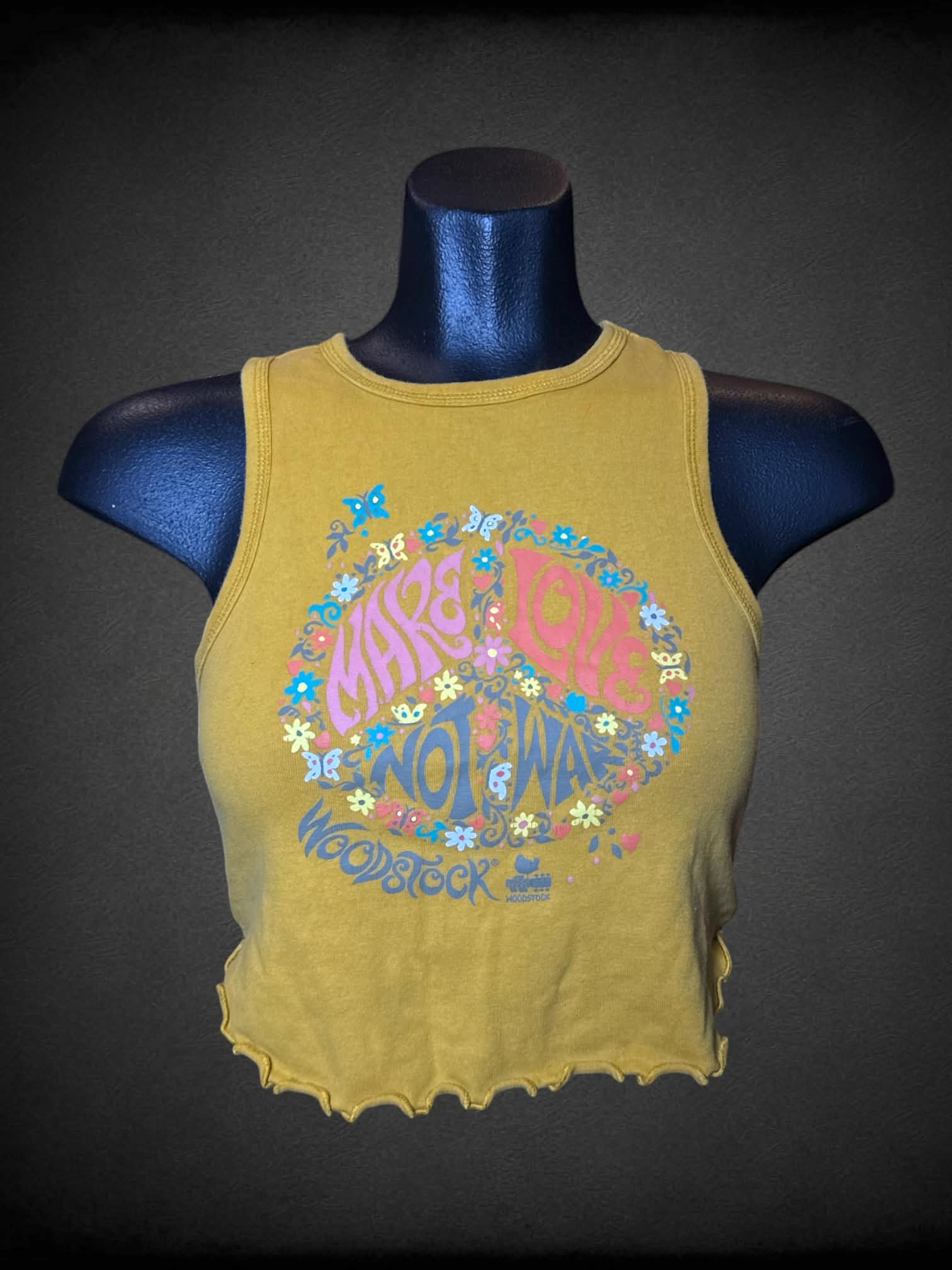 M Woodstock mustard yellow cropped tank top with “Make Love Not War” Woodstock graphic on front, and ruffle hem