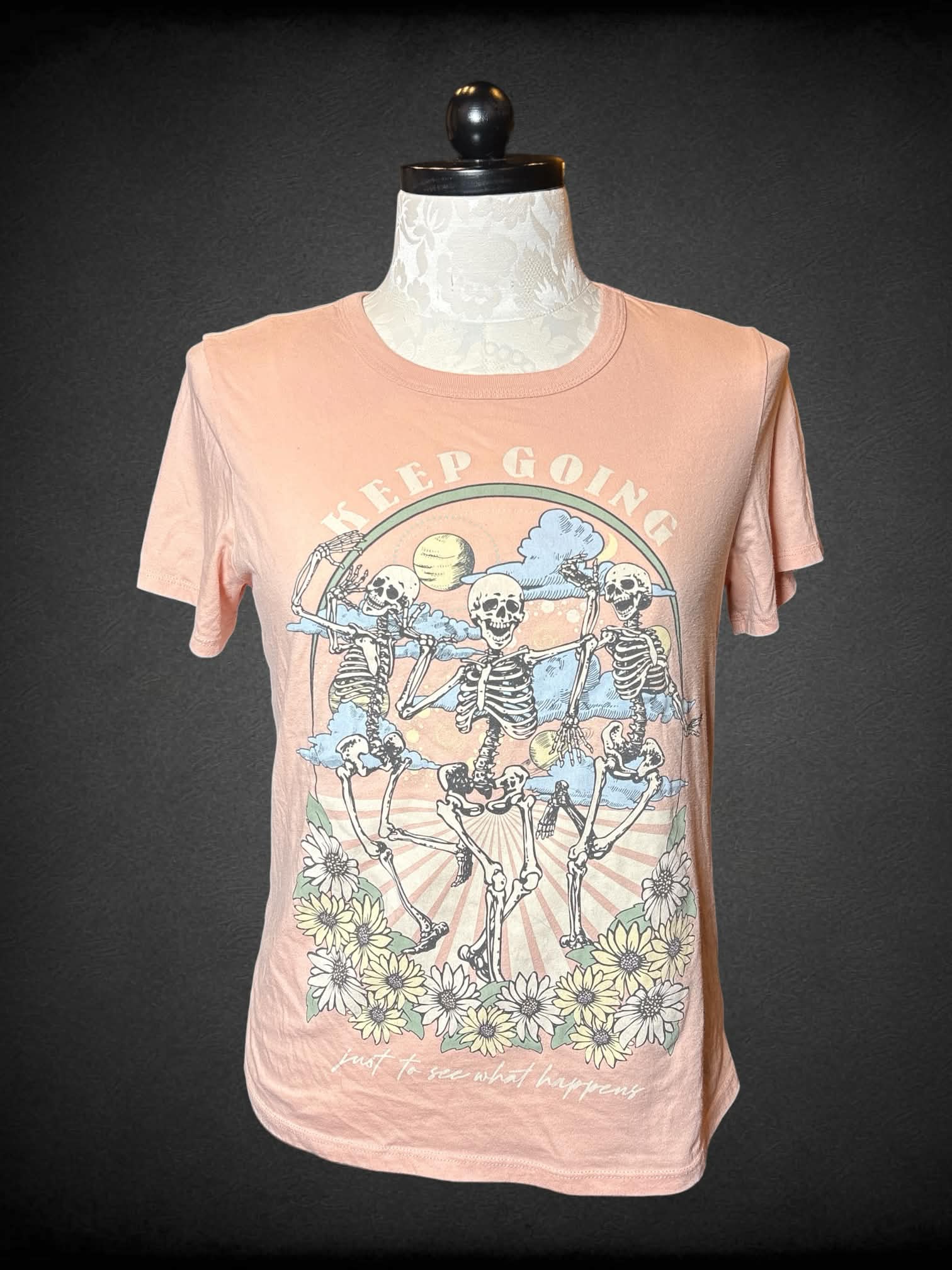 1X Zoe + Liv pink t shirt with skeleton and flower graphic with “Keep going just to see what happens” writing on front
