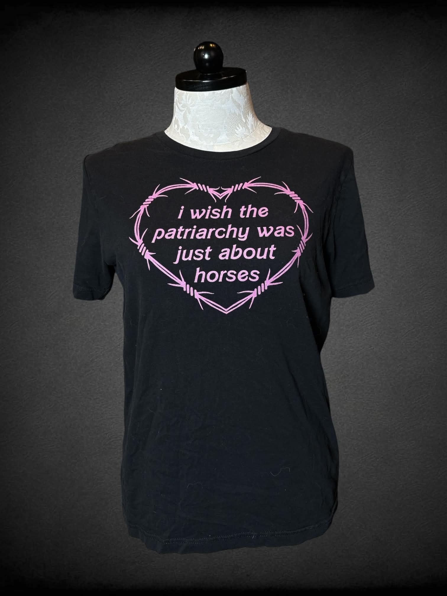 1X Canvas black t shirt with “I wish patriarchy was just about horses” barbwire heart graphic on front from the movie “Barbie”