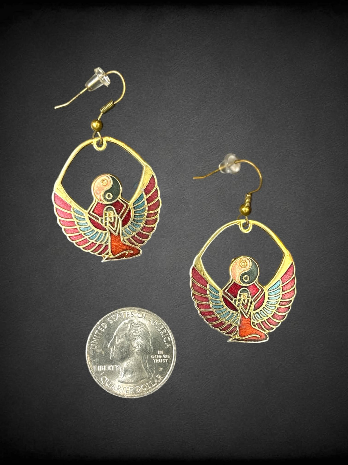Gold Egyptian revival earrings with winged goddess holding a yin-yang symbol