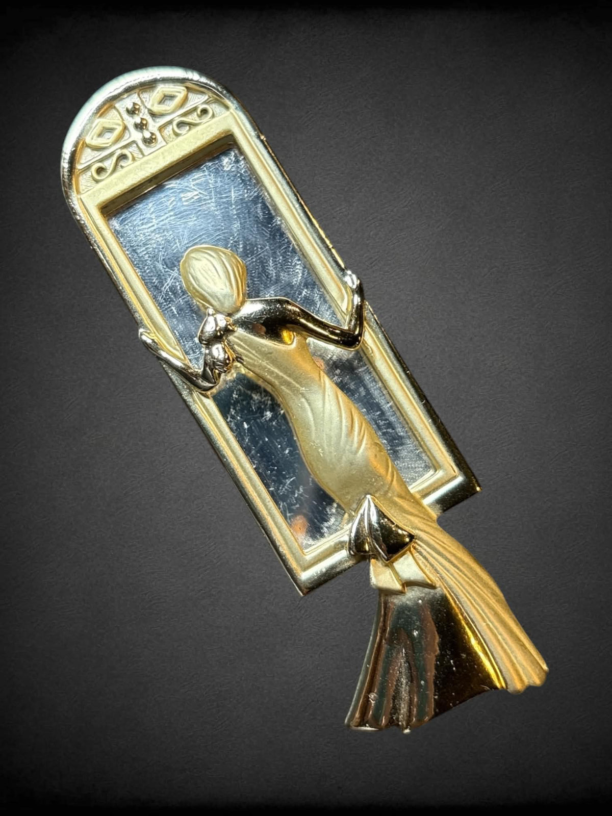 Decorative brooch of formally dressed woman standing in mirror