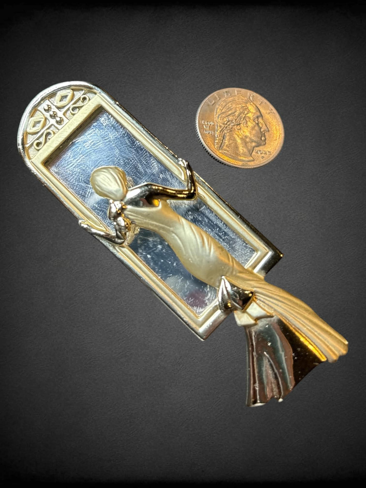 Decorative brooch of formally dressed woman standing in mirror