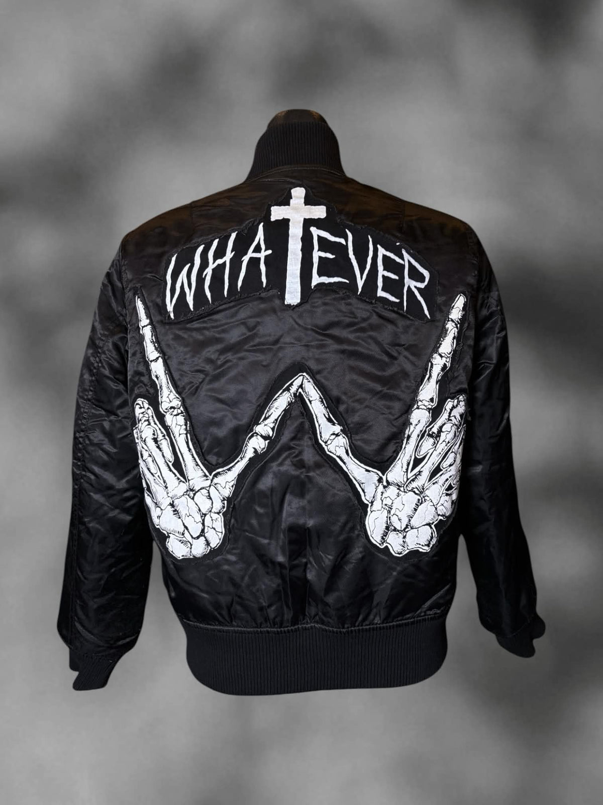 M UNIF black zip-up bomber jacket with “Whatever” skeleton hands graphic on back, and pockets