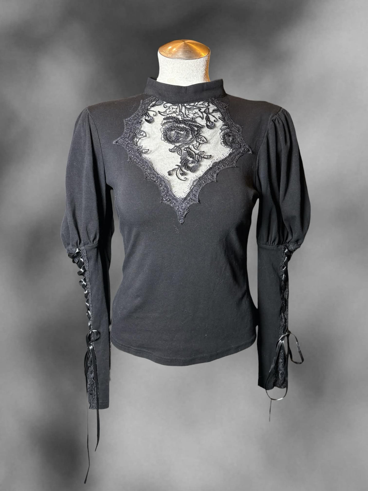 L Dark In Love black long-sleeve blouse with lace-up sleeves, embroidered mesh design on front, and button on back