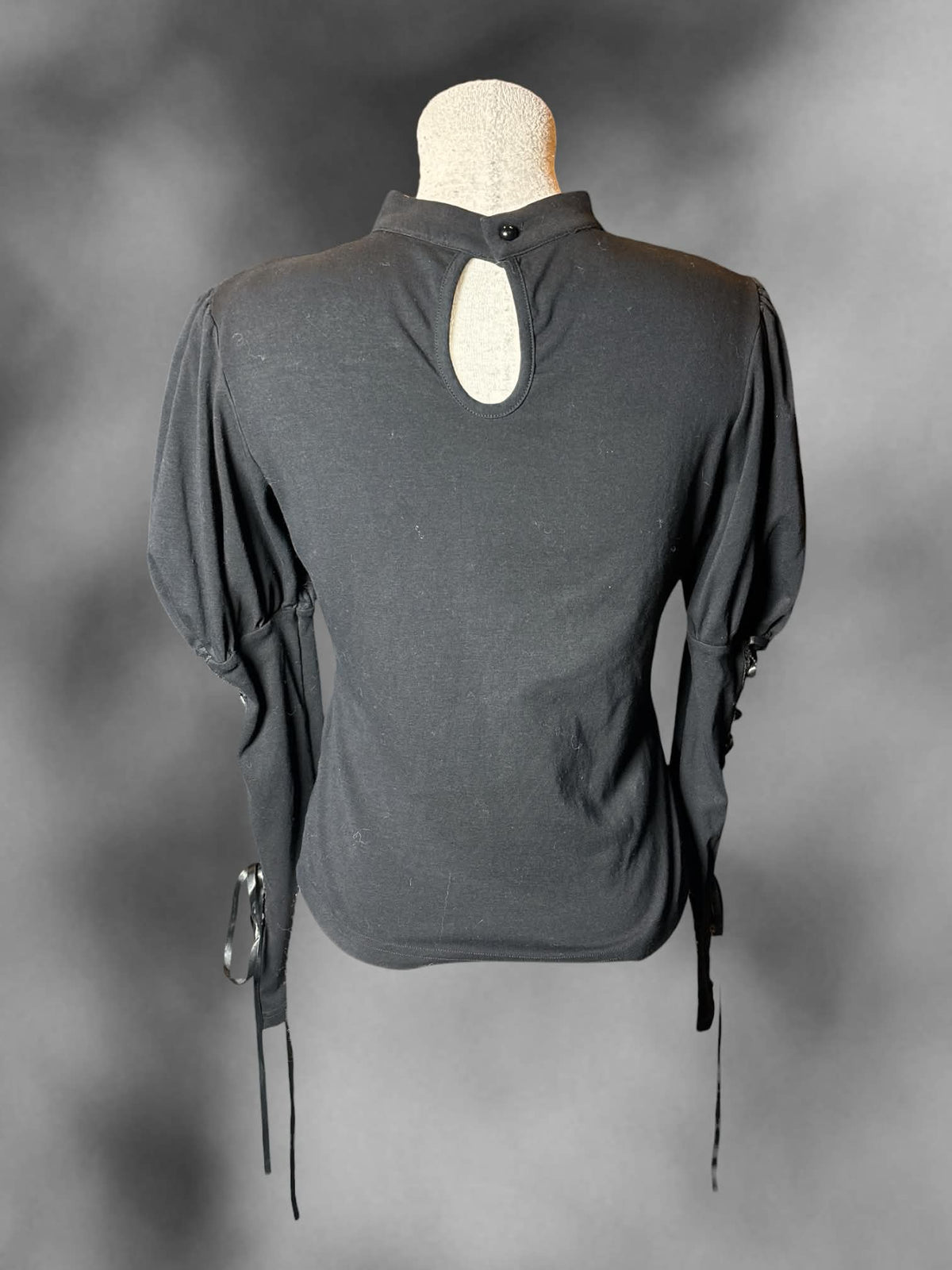 L Dark In Love black long-sleeve blouse with lace-up sleeves, embroidered mesh design on front, and button on back