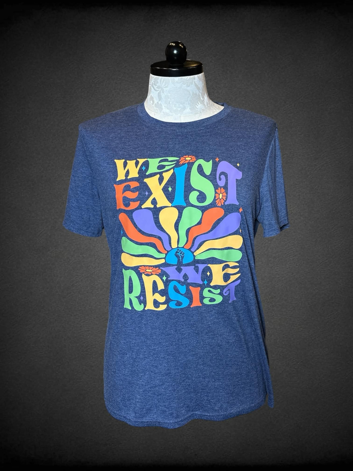 1X blue t shirt with colorful “We Exist We Resist” graphic on front