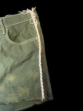 Load image into Gallery viewer, XL Green raw hem shorts w/ faded tree detail, white lace up sides, white stitching, belt loops, pockets, &amp; zipper/button closure
