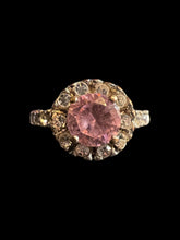 Load image into Gallery viewer, 7 Silver ring w/ round setting w/ heart cutout, round pink cut gem surrounded by small white gems, &amp; white gems on band
