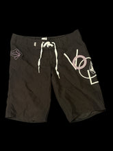 Load image into Gallery viewer, M Black shorts w/ &quot;Volcom&quot; brand embroidered design, velcro pocket, pink stitching detail, &amp; zipper to lace/velcro closure
