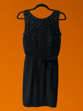 Load image into Gallery viewer, S Vintage union made 60&#39;s black sleeveless dress w/ tank top lining, sequined lacey crisscross design on top, &amp; black velvet bow on bottom
